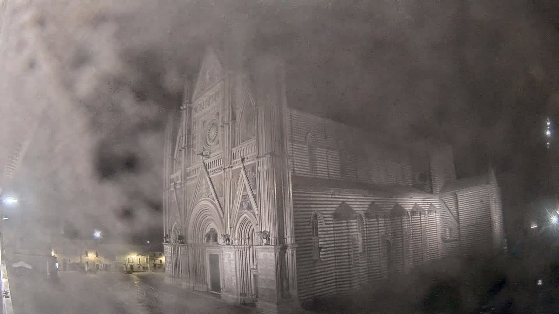 A large, ornate cathedral is partially obscured by heavy fog or mist at night.