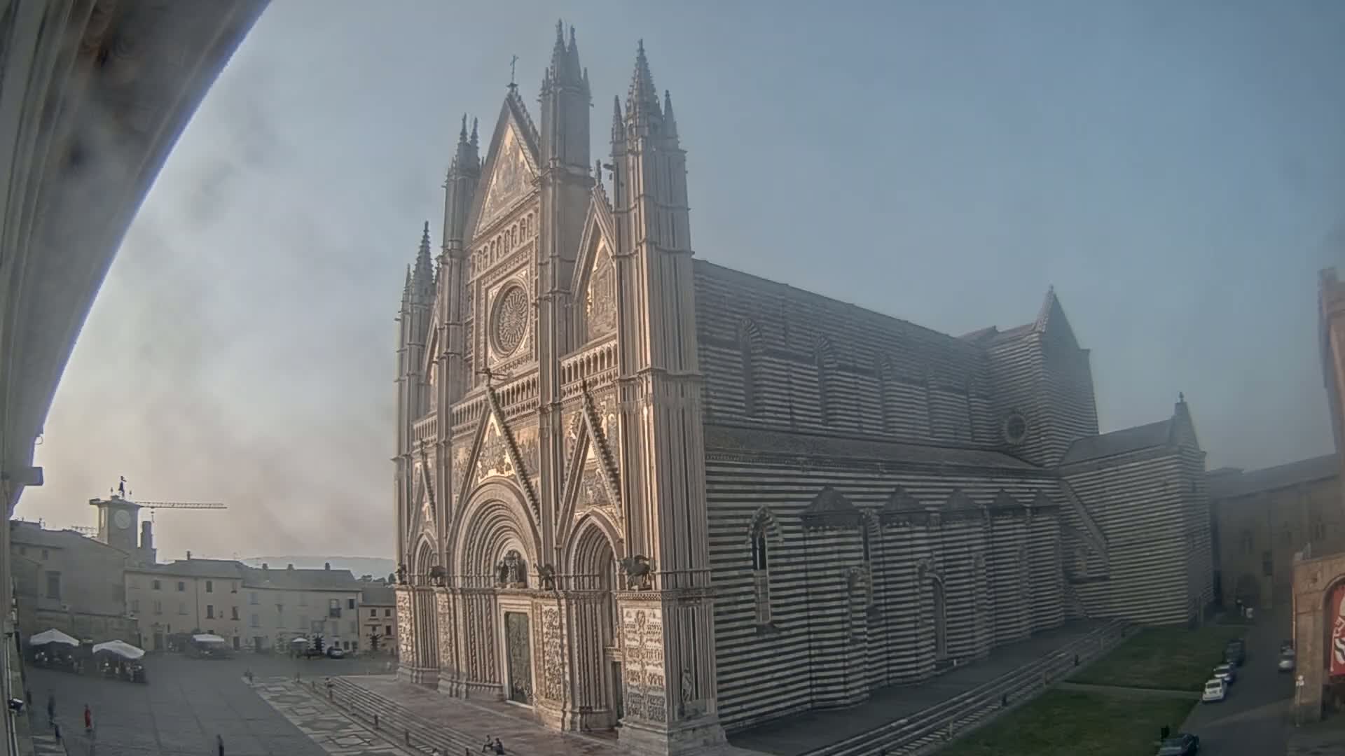 A large, striped cathedral stands in a hazy, possibly foggy,  town square.