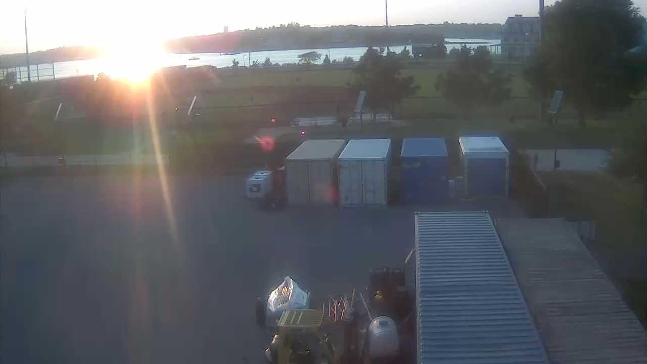 At night, several vehicles and shipping containers are parked in a dimly lit, outdoor lot.