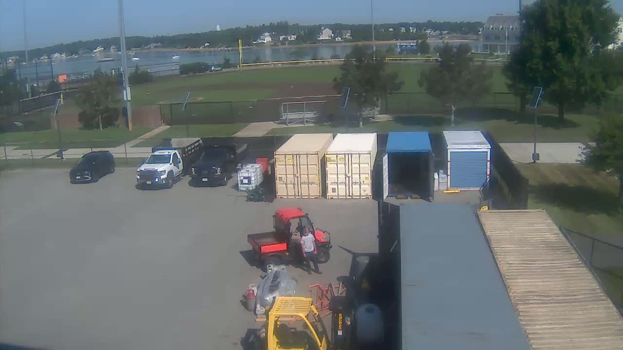 At night, several vehicles and shipping containers are parked in a dimly lit, outdoor lot.