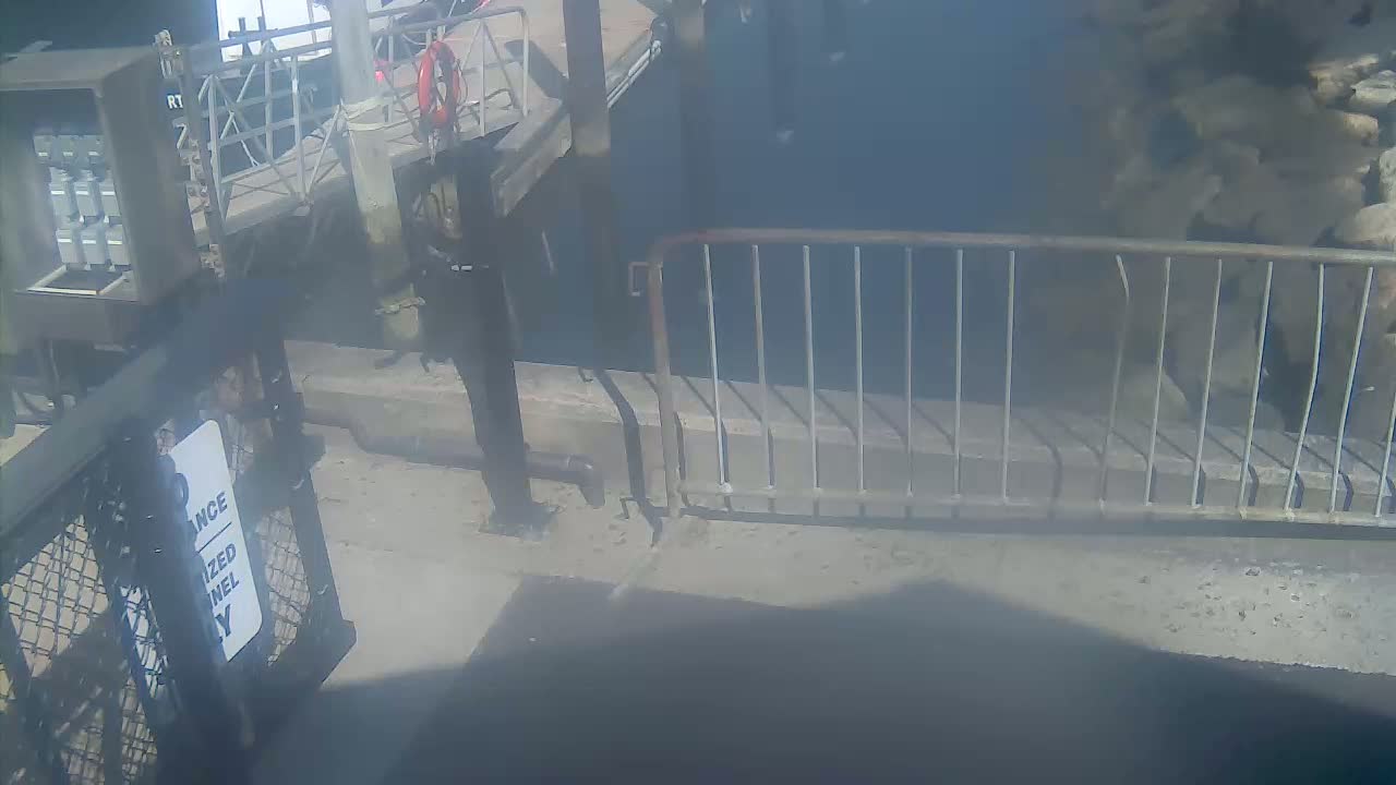 A dimly lit, dark area shows a metal barricade and a person standing near a "no admittance" sign.