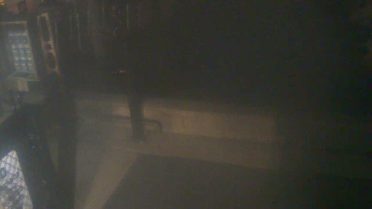 The image is an extremely dark and blurry interior shot, faintly revealing a device with a grid pattern on the left, alongside indistinct vertical and horizontal structures.