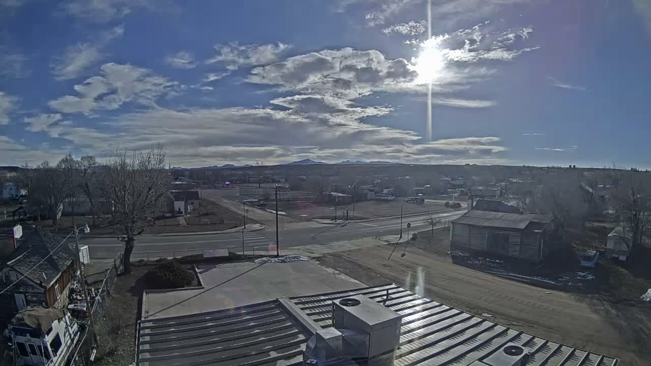 An elevated view captures a snow-covered town at night, with streetlights illuminating the freshly fallen snow on roads and rooftops under cold, clear skies.
