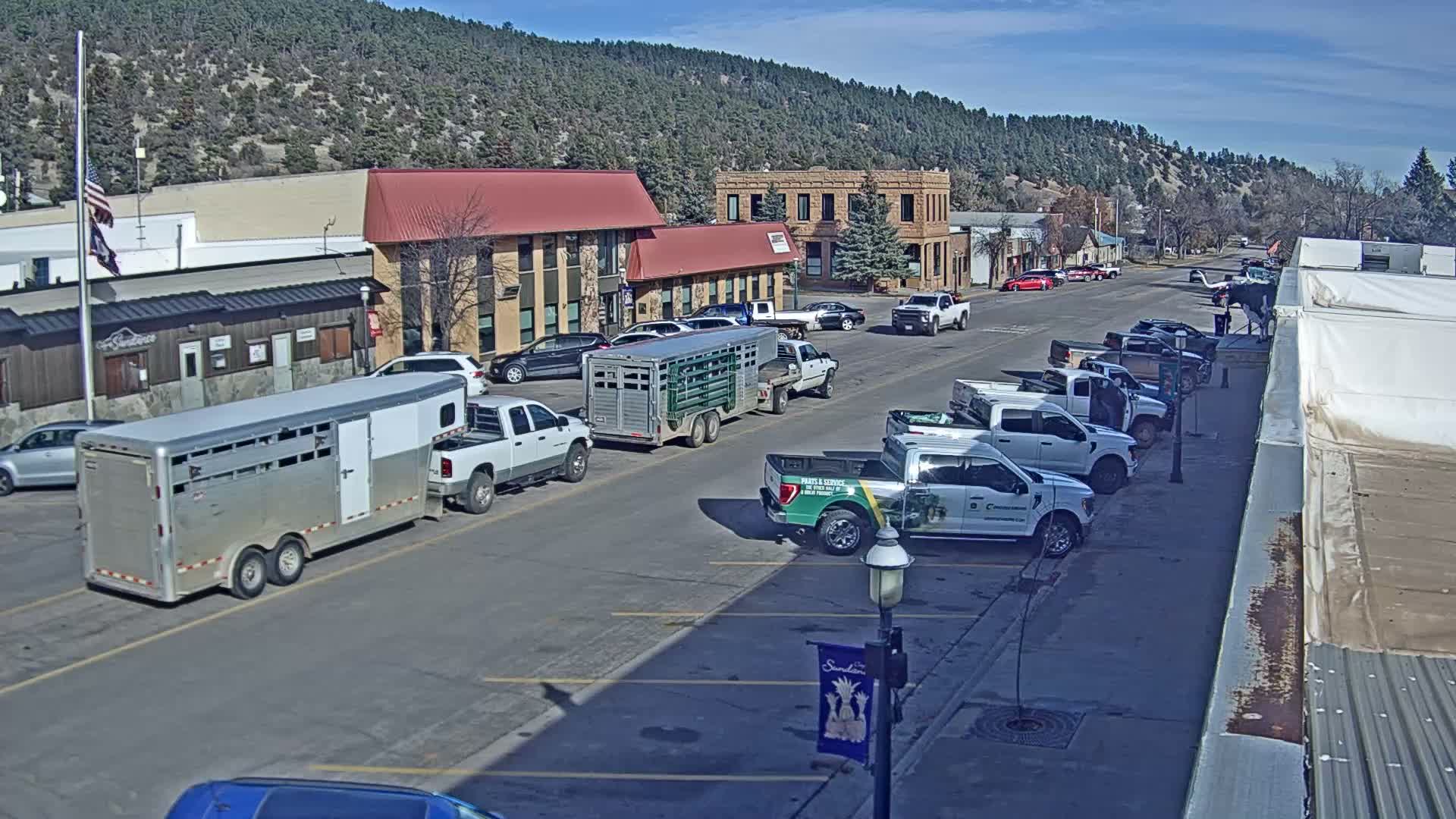 An empty town street is brightly illuminated by numerous streetlights at night, under clear weather conditions.