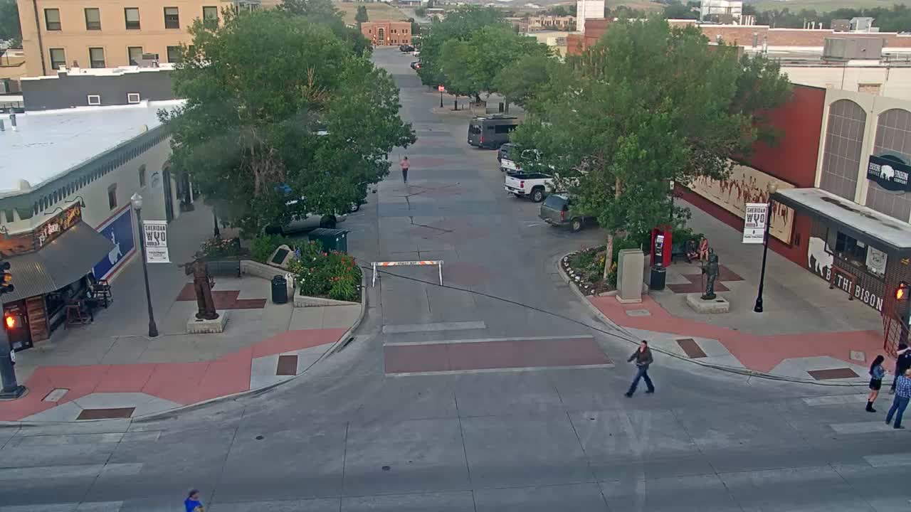 A red trailer carrying two tents sits in a mostly empty town square at night, under partly cloudy skies.