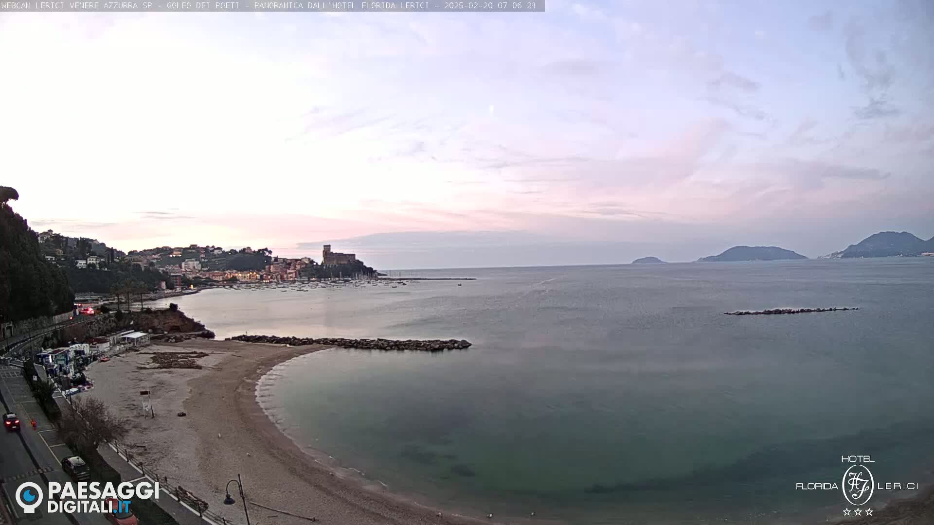 A coastal town with a sandy beach and calm sea is visible under a pale, dusky sky.