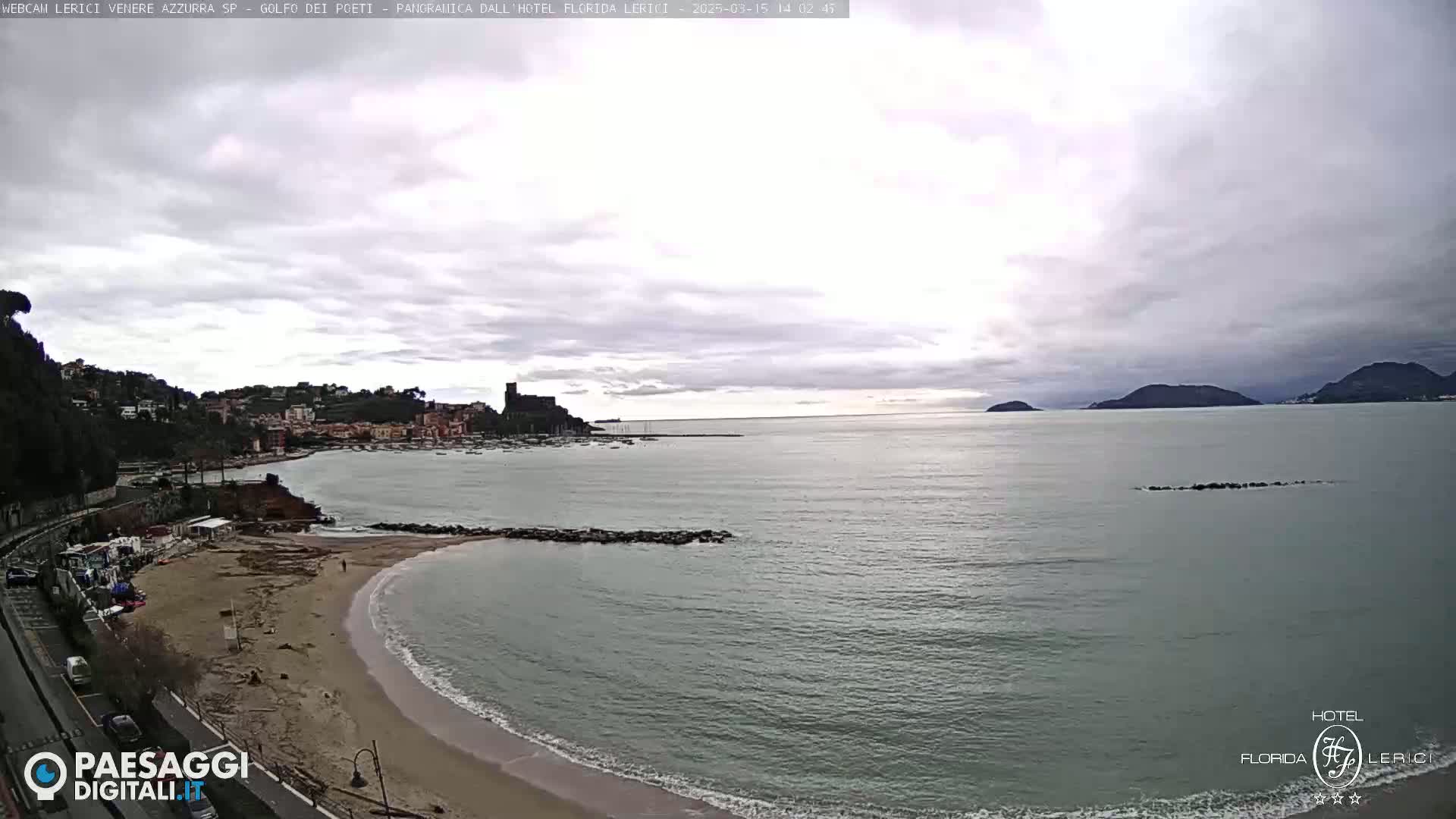 A coastal town with a sandy beach and calm sea is visible under an overcast sky.