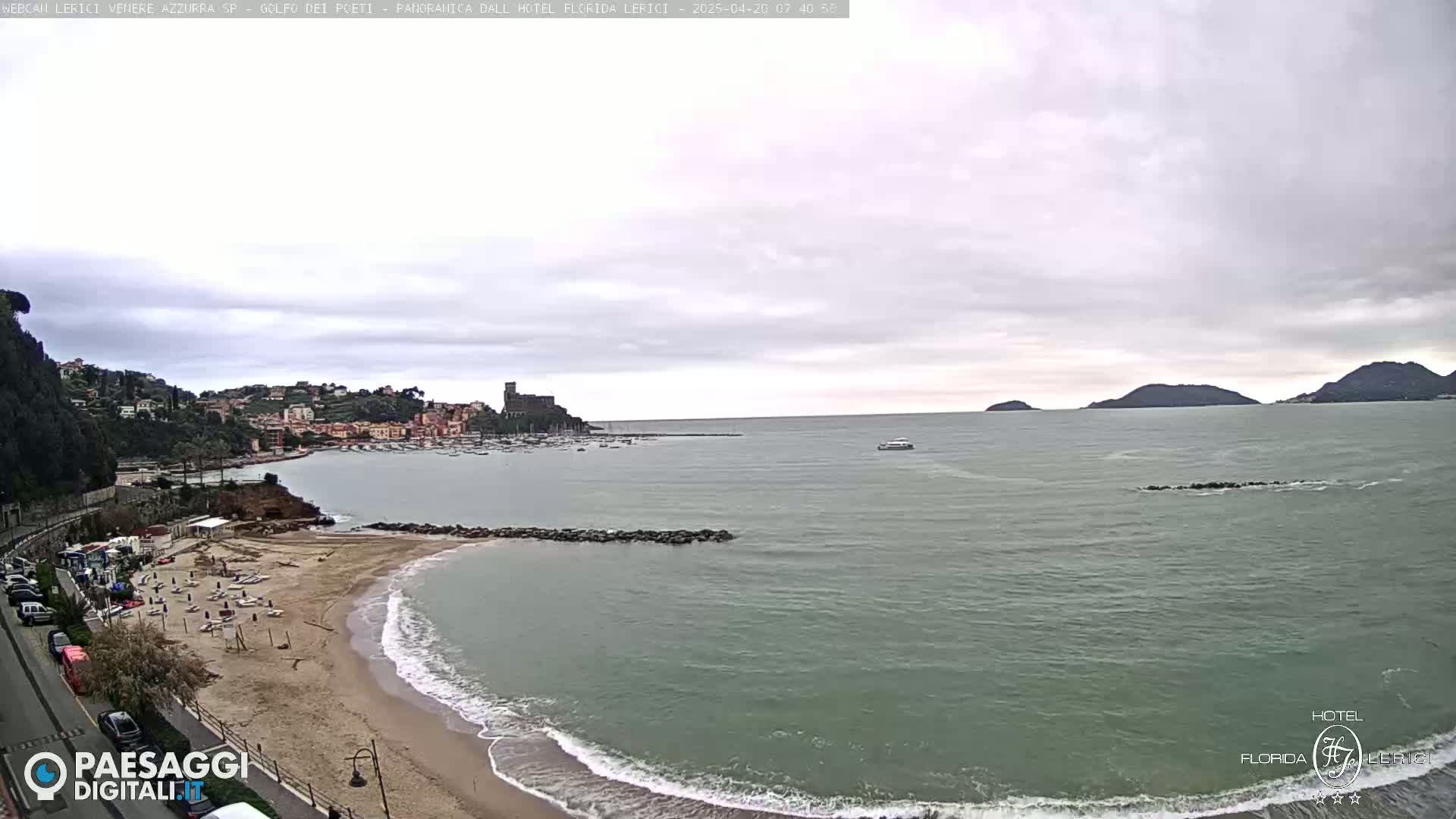 A coastal town with a sandy beach and calm sea under an overcast sky.