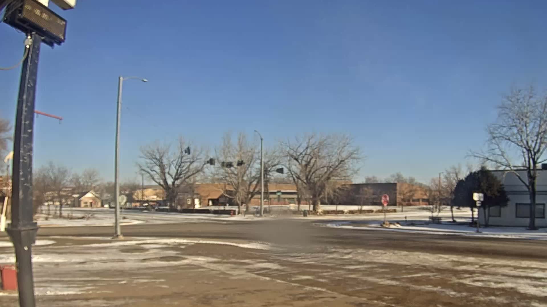 A hazy night scene captures a fire burning on a building's roof on the left, with multiple bright streetlights illuminating a street and bare trees under a dark sky.