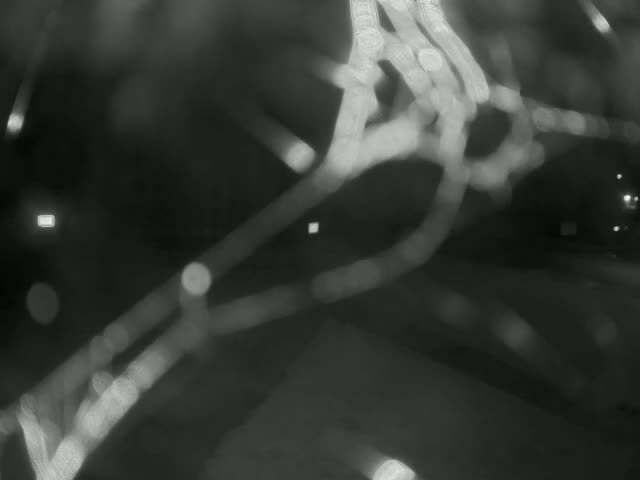A blurry, out-of-focus image shows bright, light streaks and bokeh against a dark background, possibly taken at night in snowy conditions.