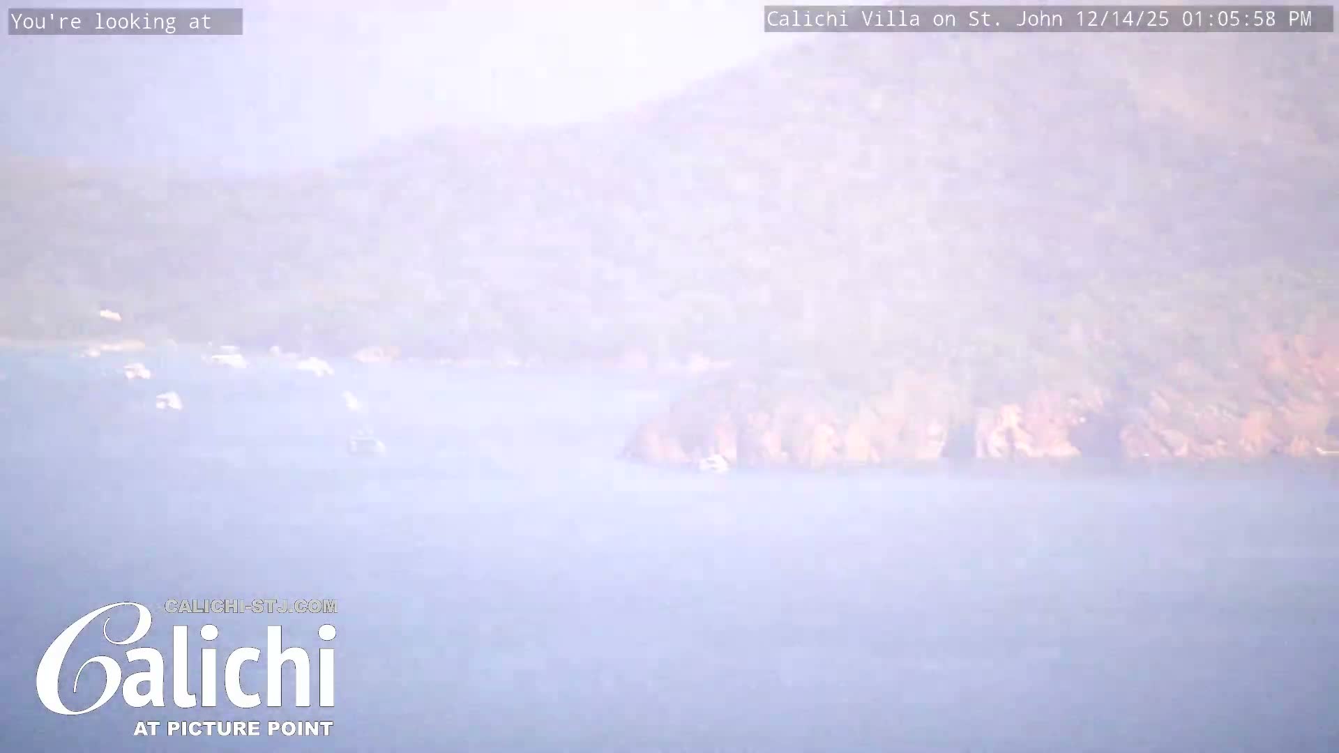 A dark, nighttime outdoor scene displays scattered clusters of distant lights across a landscape, beneath a partly cloudy sky with a faint, low-lying mist or fog.