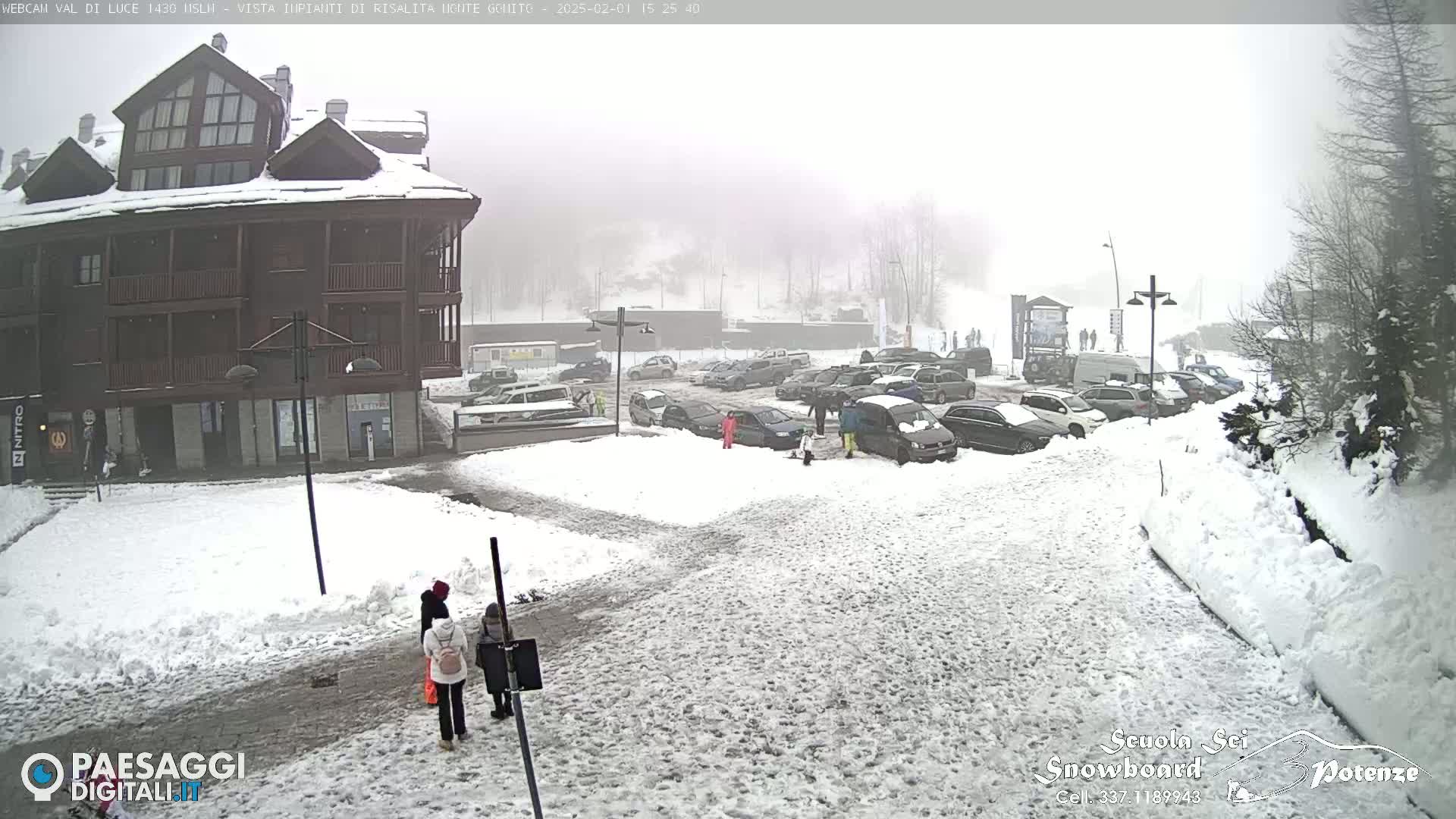 A snow-covered parking lot with several cars and a multi-story building is visible in a heavy, foggy snowstorm.