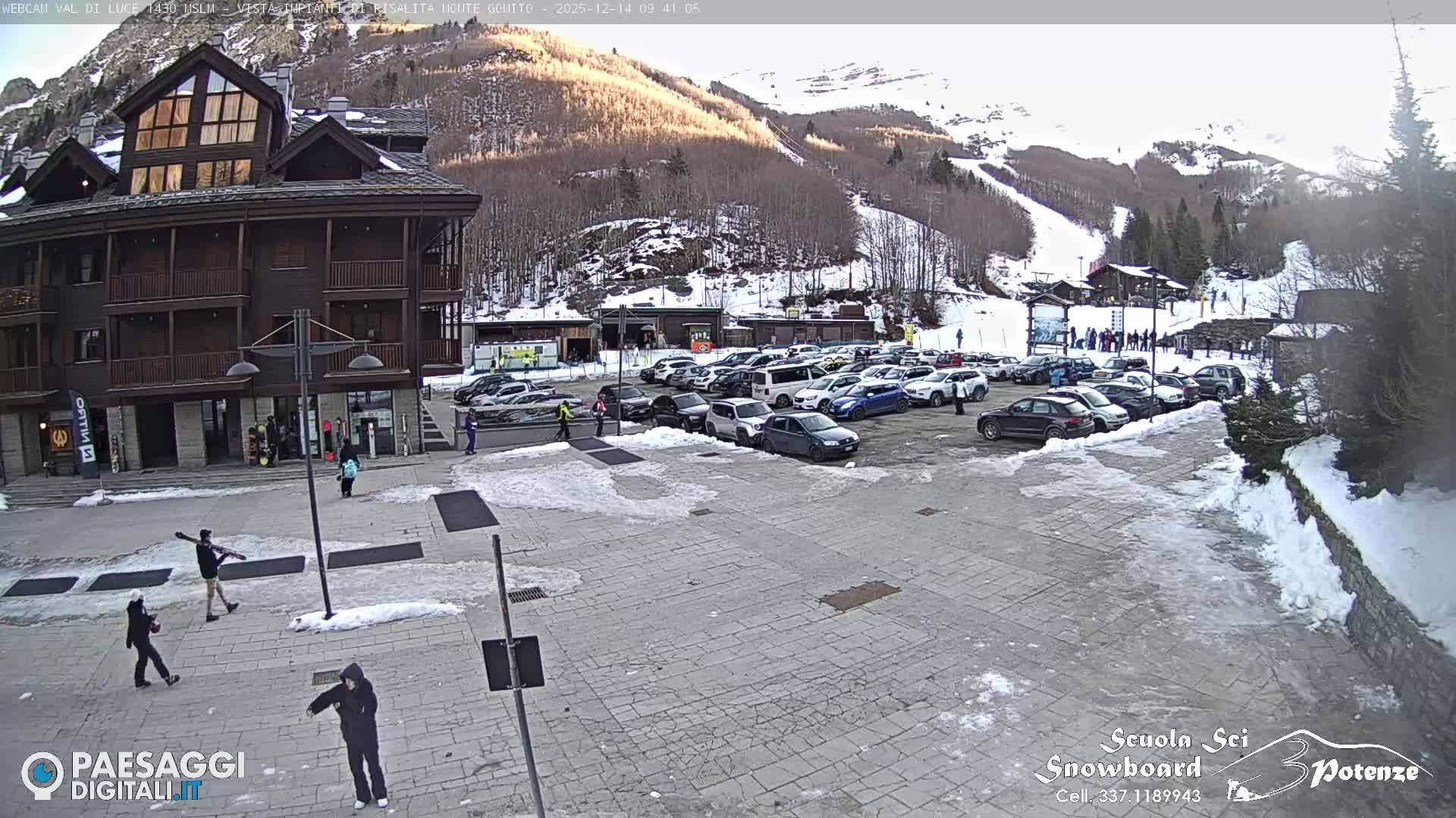 A multi-story building and a busy parking lot are visible amidst a snowy landscape on a heavily fogged winter day.