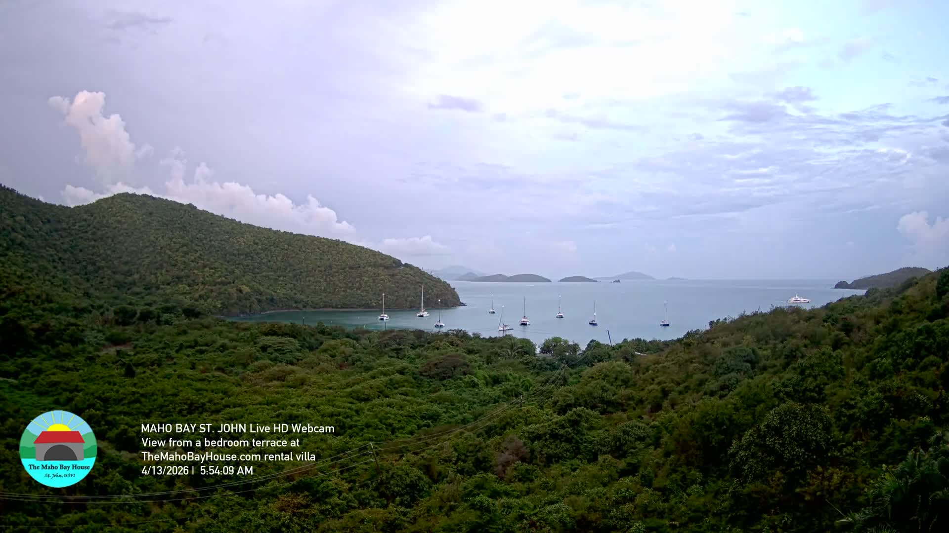 A dark, cloudy night reveals a bay with scattered lights from boats and a distant shore, framed by shadowed hills.