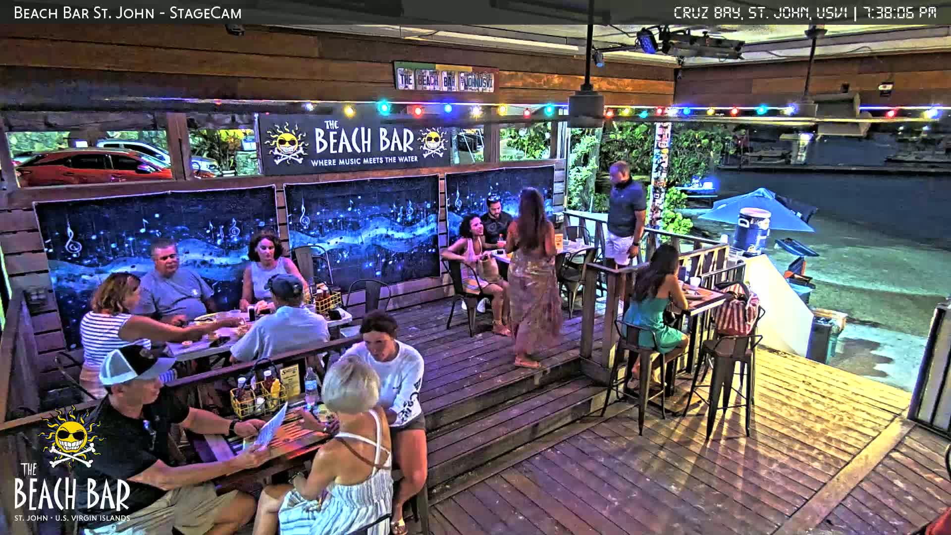 A dimly lit outdoor bar area with empty tables and chairs at night.