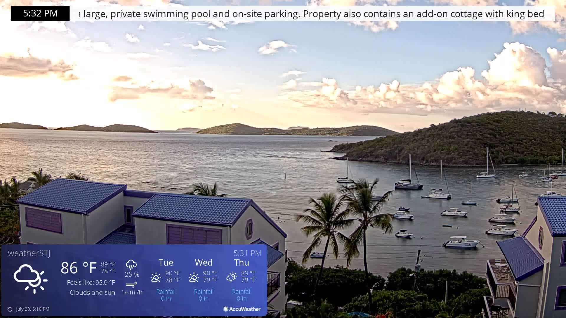 A partly cloudy sunset over calm water, showing several sailboats moored in a bay, with houses and palm trees visible in the foreground.