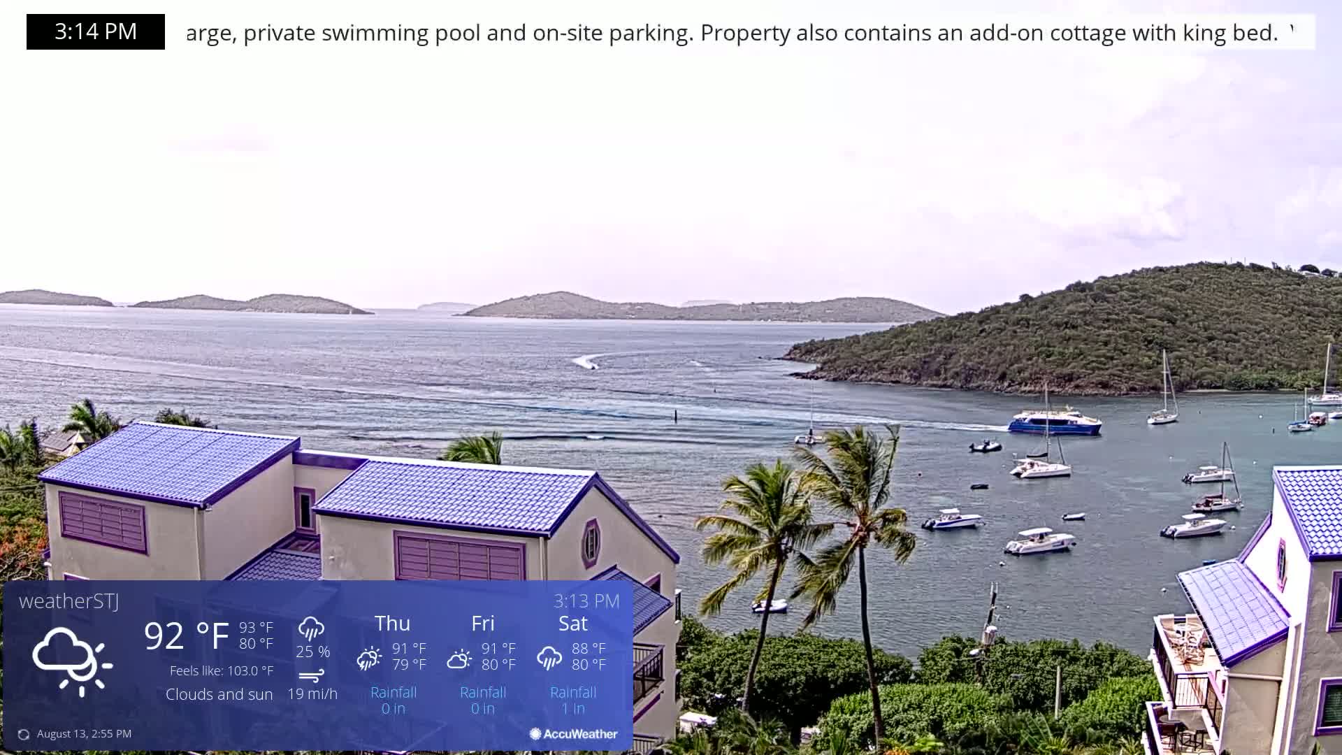 A partly sunny, breezy scene shows a calm bay with several boats, a distant shoreline, and a couple of buildings with purple roofs in the foreground.