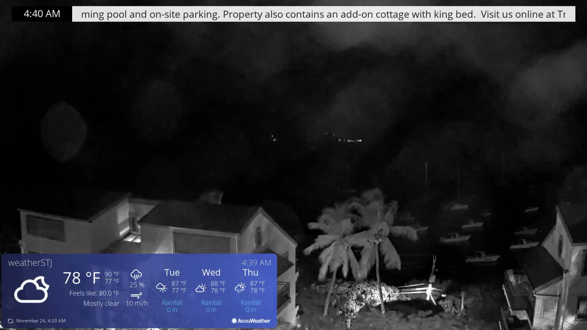 A dark, mostly clear night at 78°F with a light breeze reveals a coastal scene with several buildings and palm trees in the foreground, overlooking numerous boats moored on the water, and faint lights visible on a distant shore.