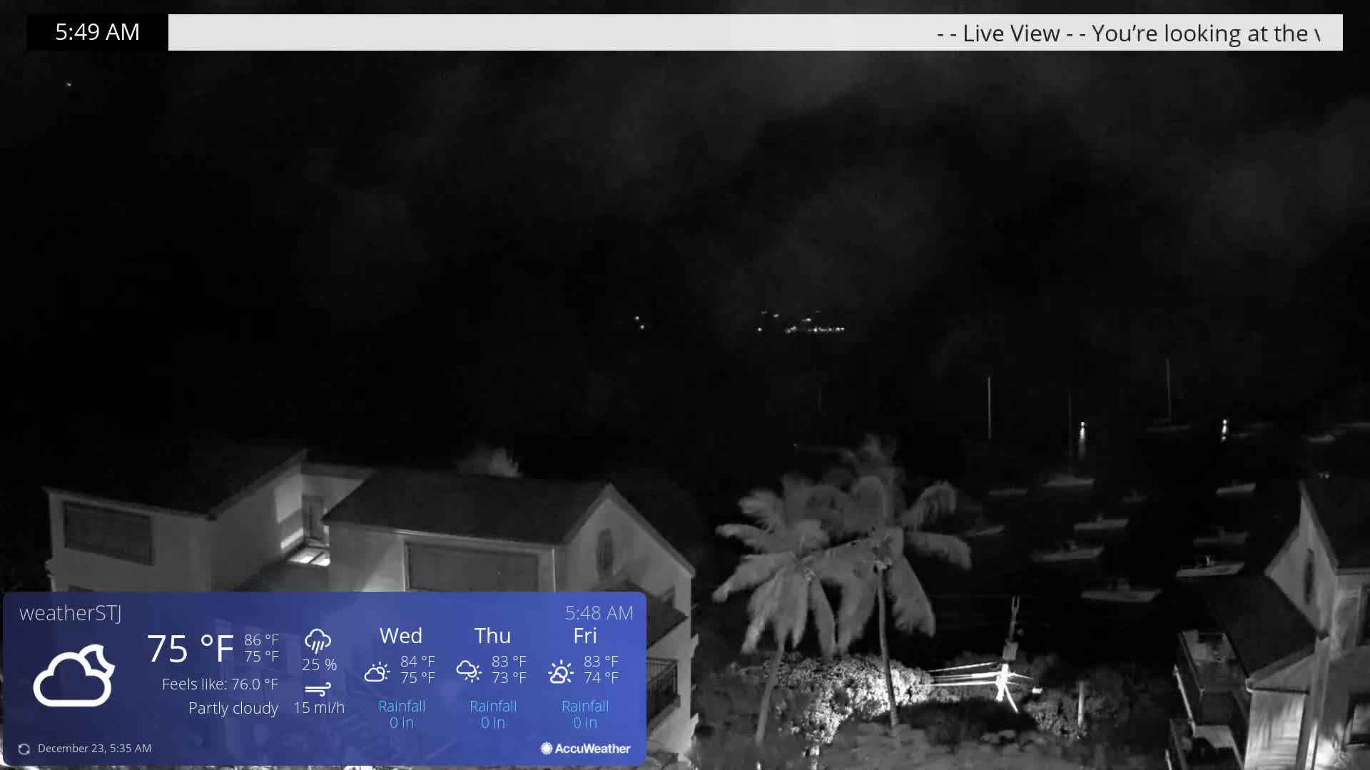 An early morning view of a harbor, showing houses, palm trees, and numerous boats on the water, under partly cloudy skies with a temperature of 75°F.