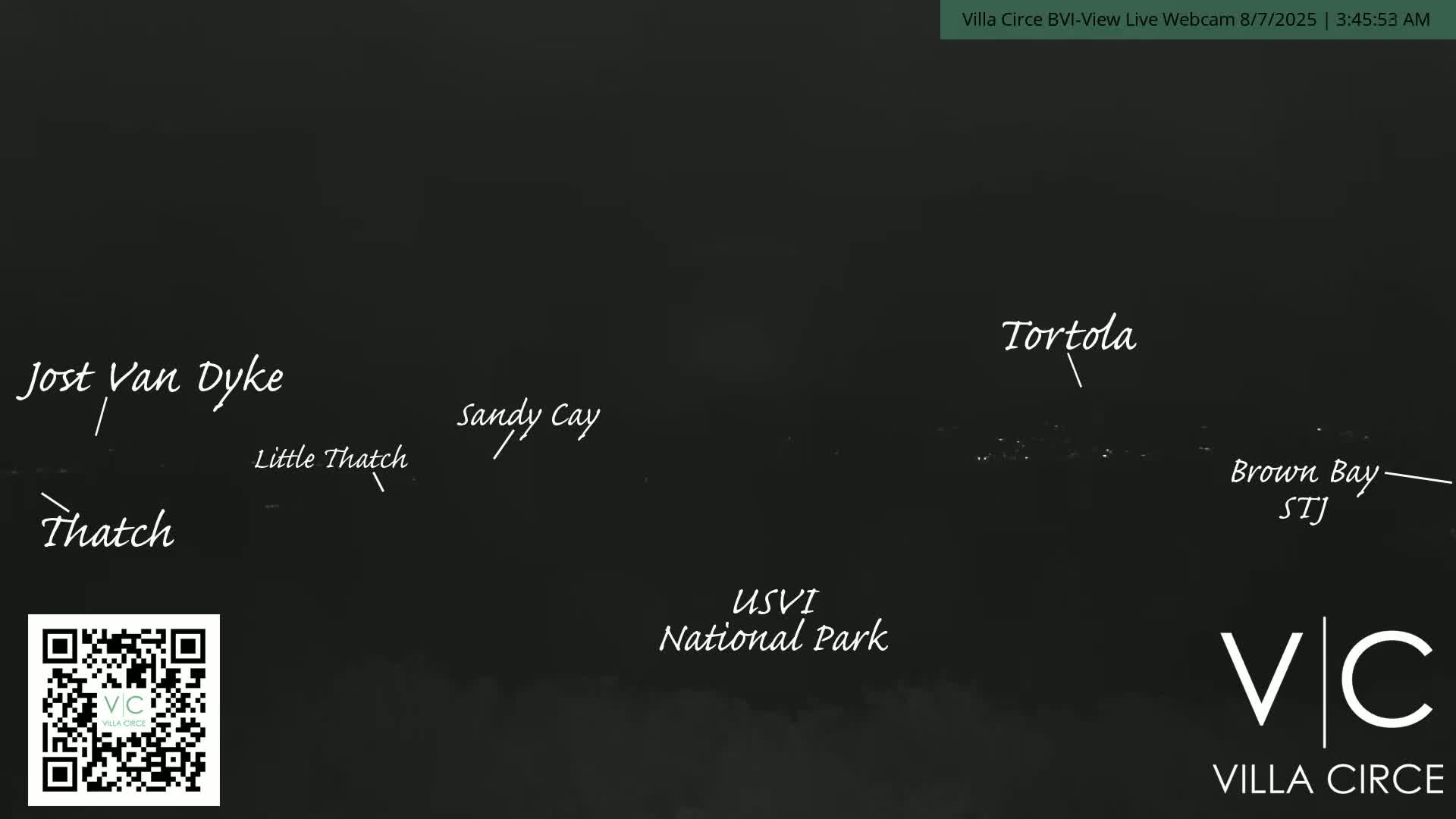 A nighttime, dark view of a coastline, showing lights in the distance.