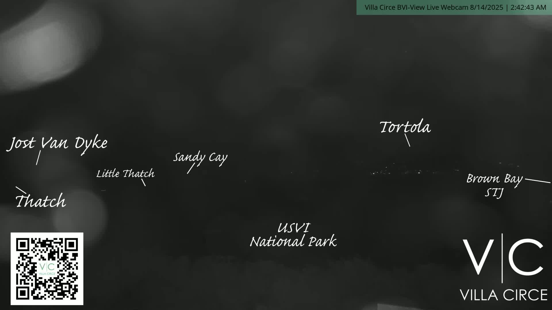 A nighttime, blurry long shot of a coastal area shows lights in the distance.