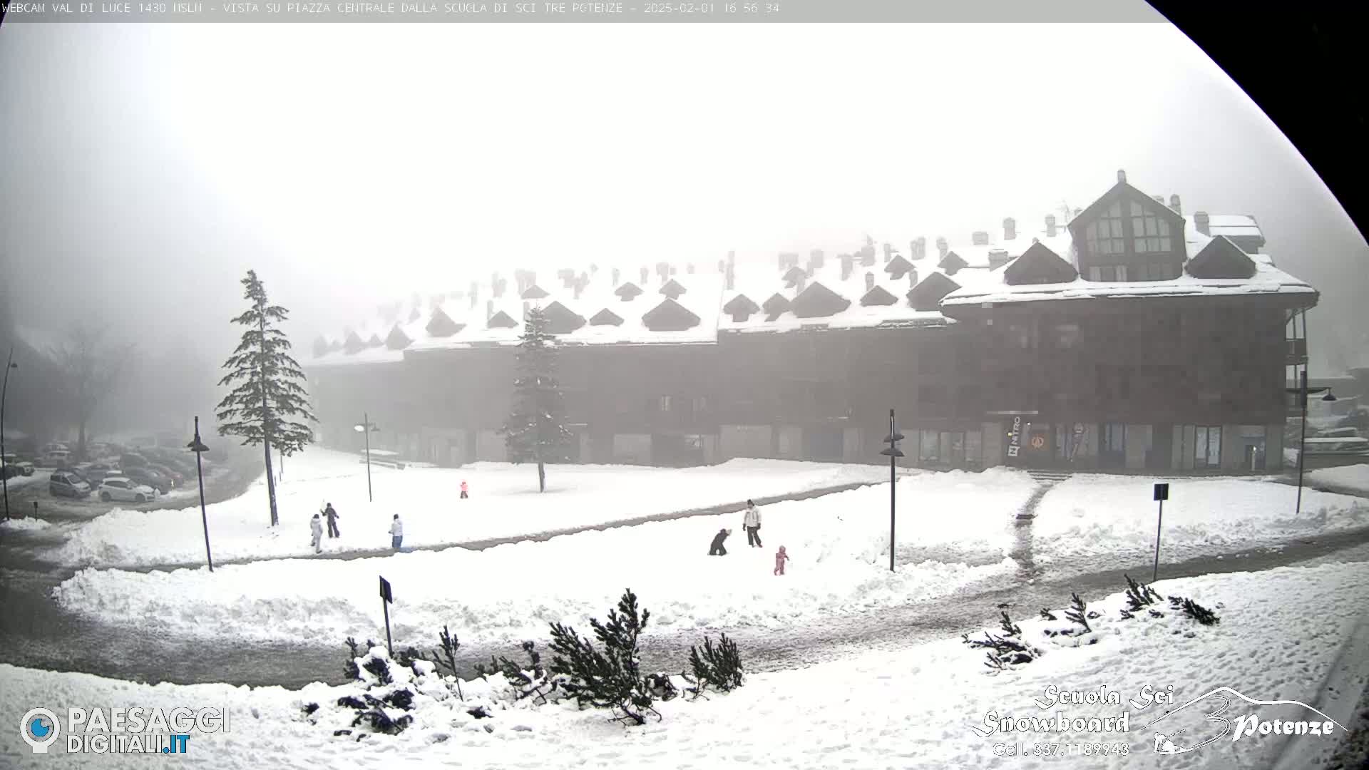 A snow-covered plaza with a multi-story building in the background, under foggy conditions.