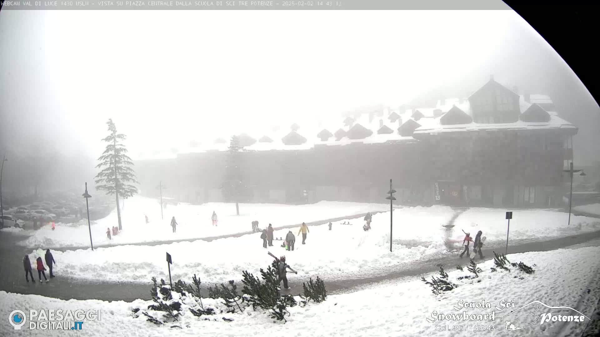 A snow-covered plaza with several people and buildings is visible in heavy fog.