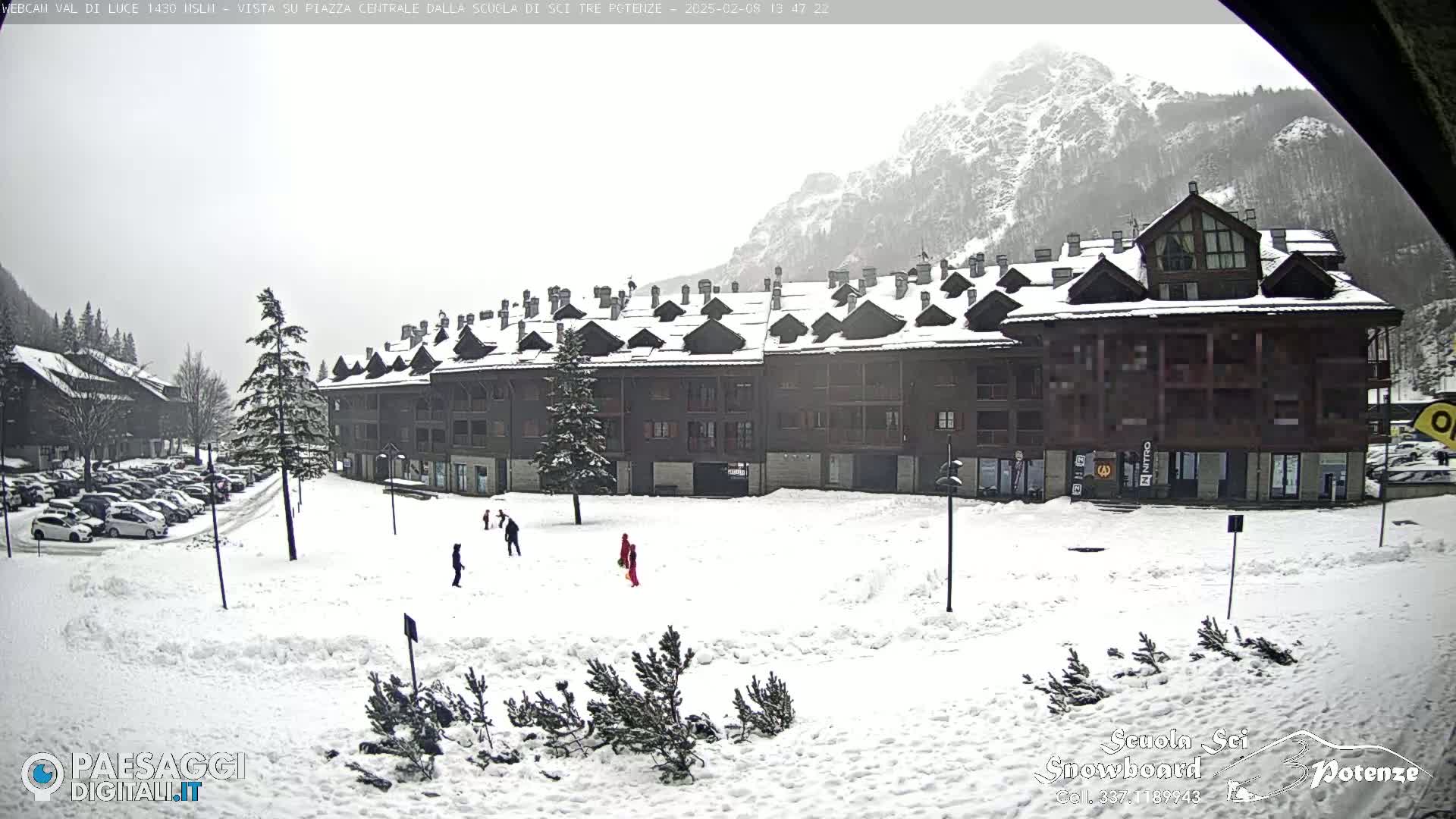 A snow-covered plaza with a multi-story building in the background, under an overcast sky.