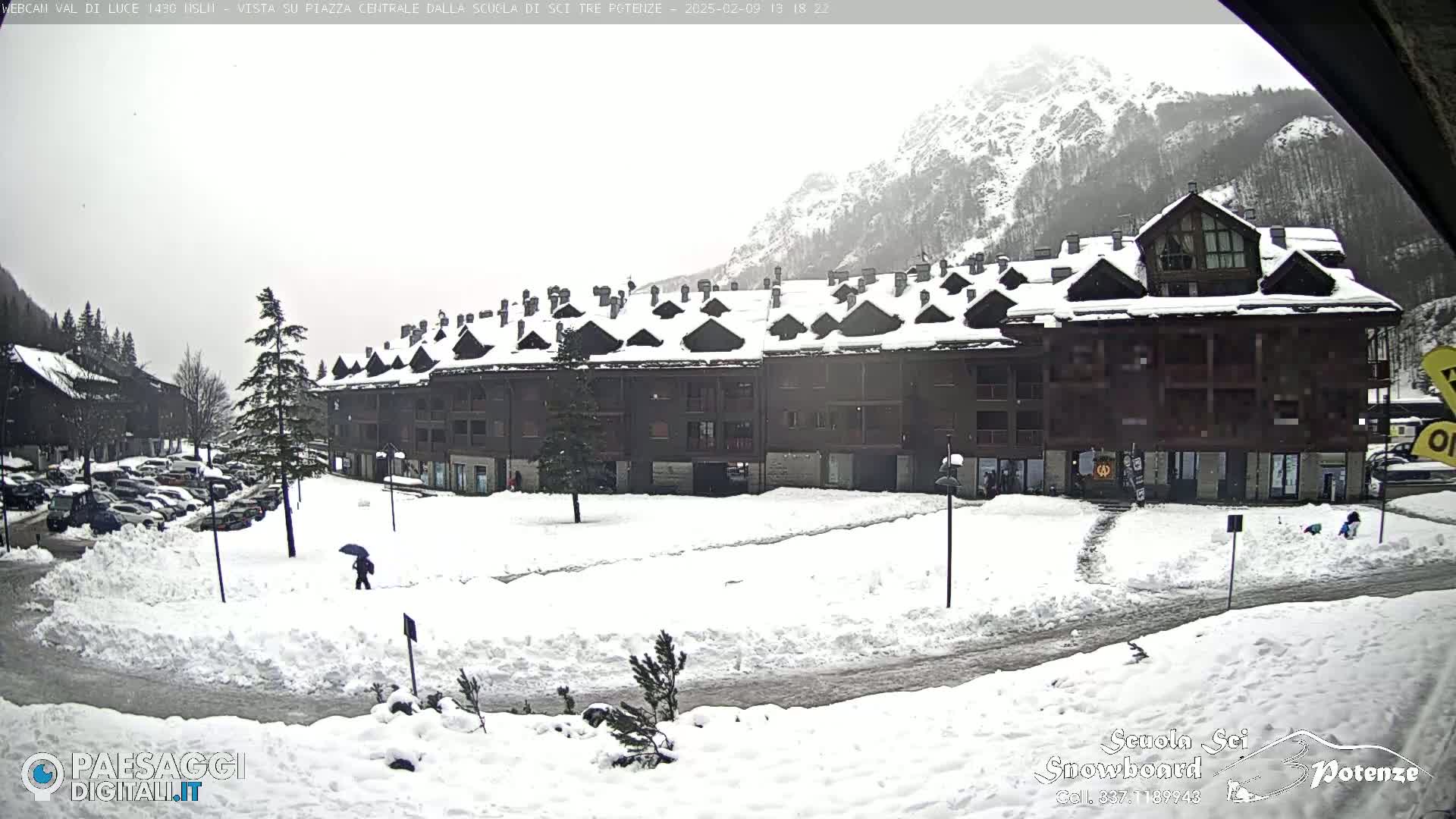 A snow-covered plaza with a multi-story building in the background, under an overcast sky.