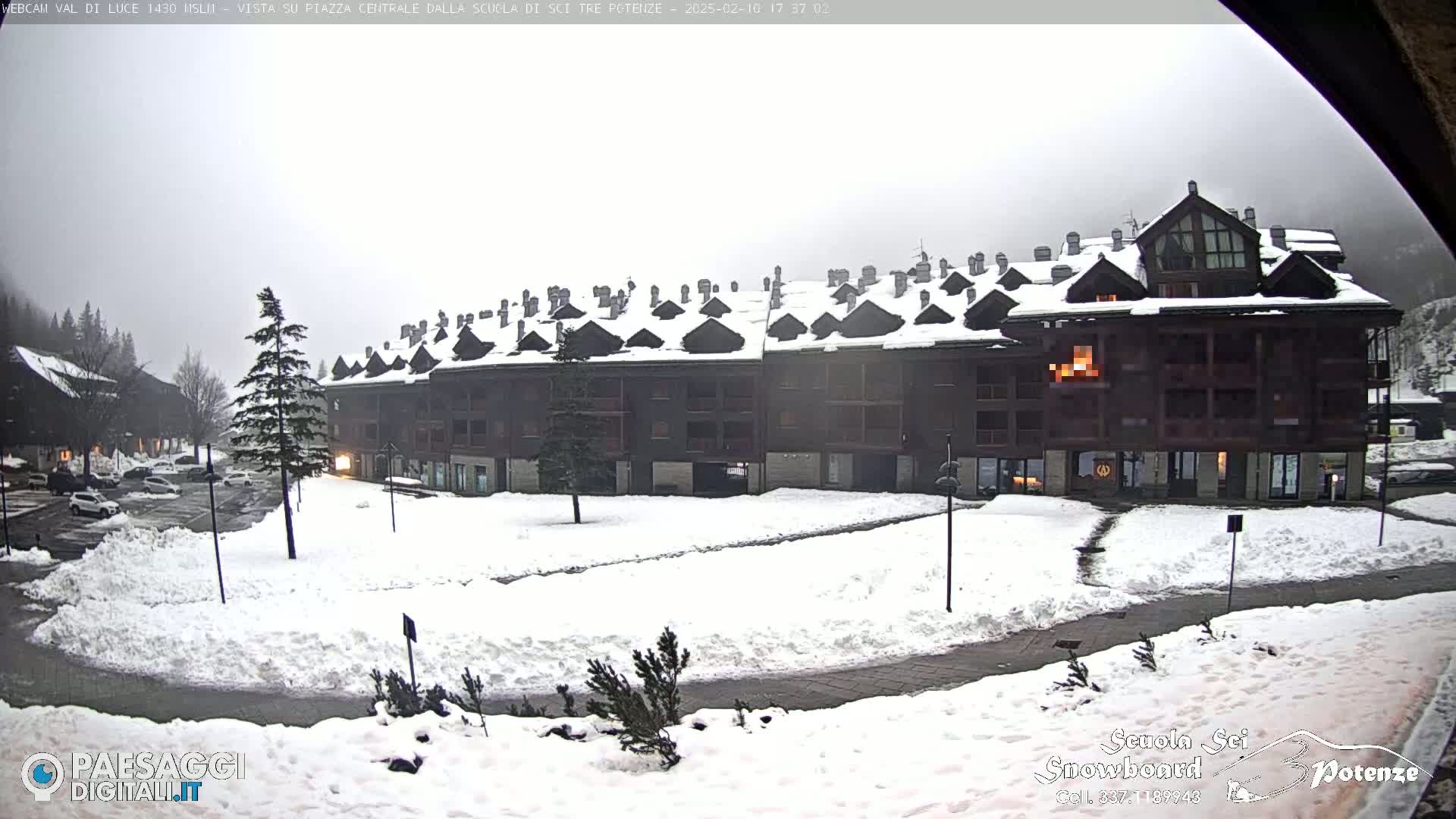 A snow-covered plaza sits in front of a multi-story building under an overcast sky.