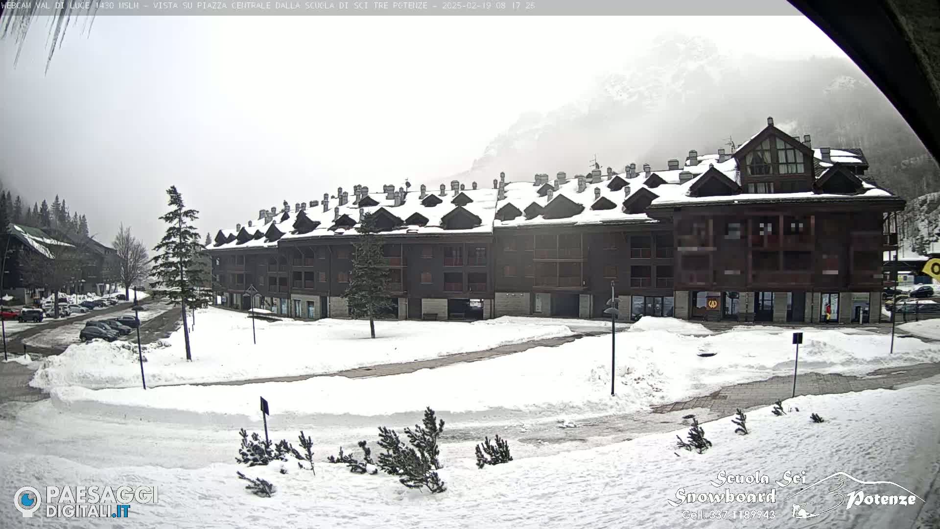 A snow-covered plaza with a large, multi-story building in the background on an overcast day.