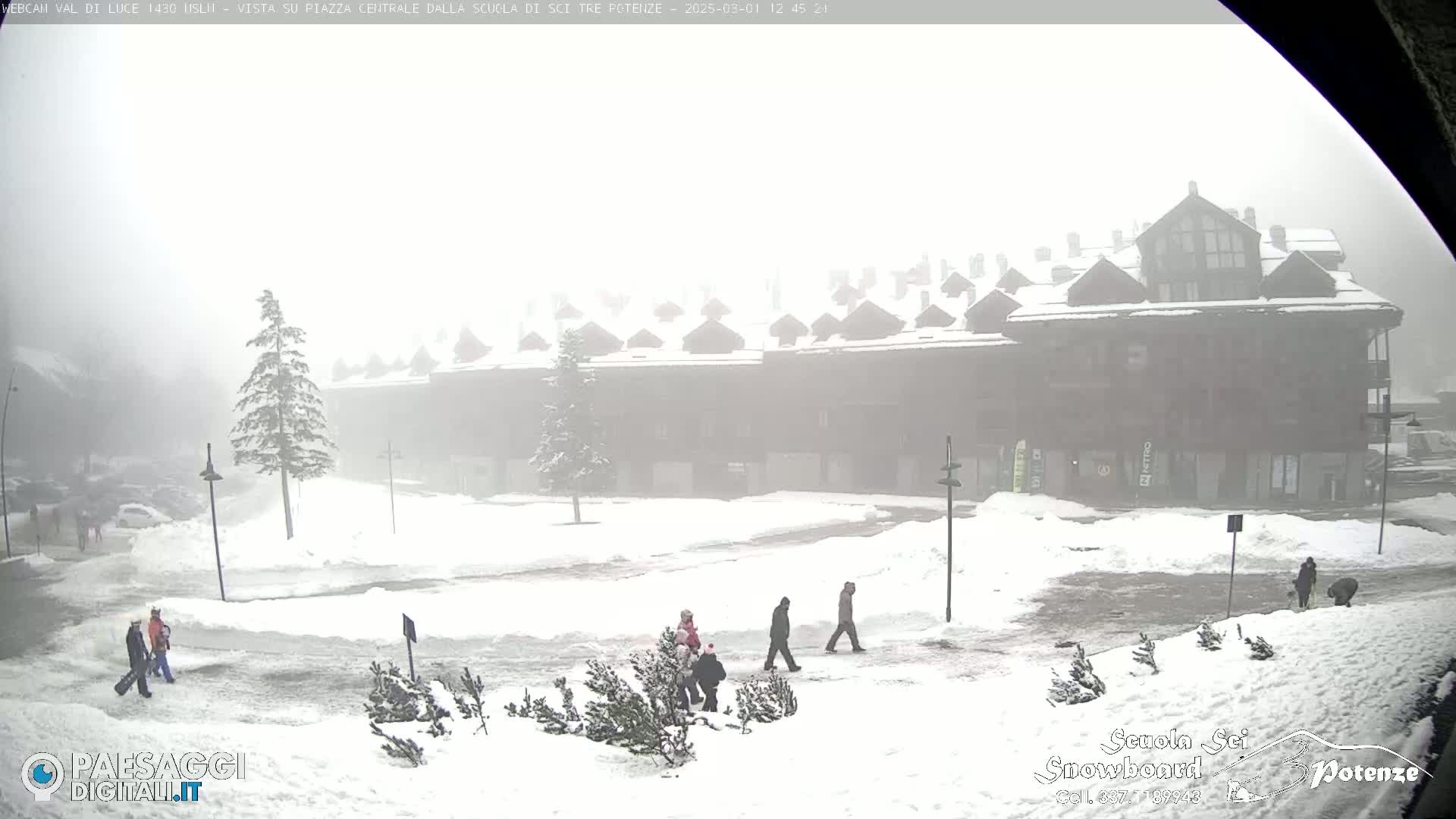 A snow-covered plaza with a large building in the background is shrouded in fog.