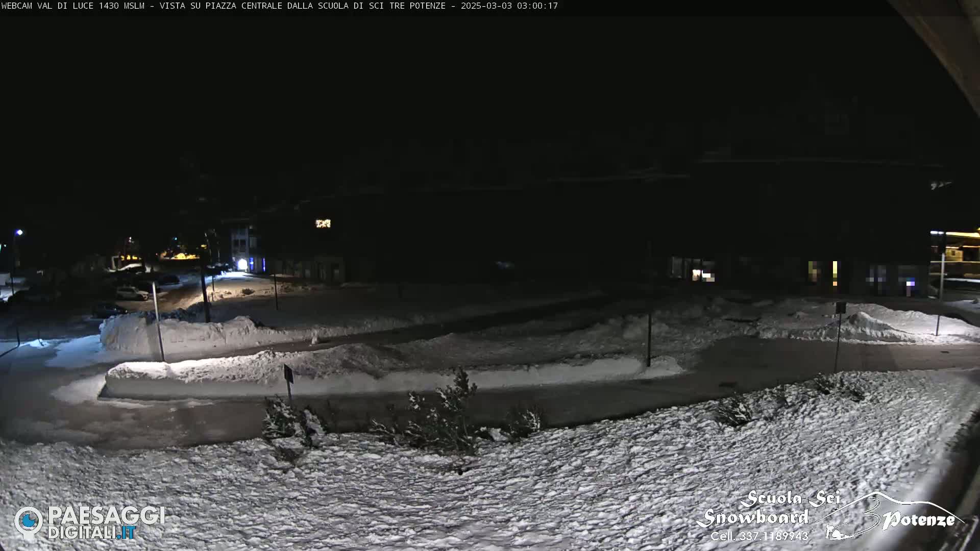 A snow-covered street scene at night, illuminated by streetlights.