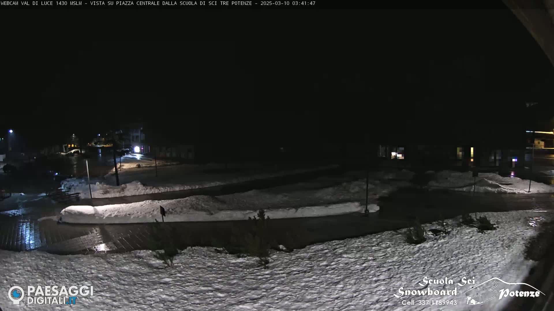 A snow-covered plaza is dimly lit at night.