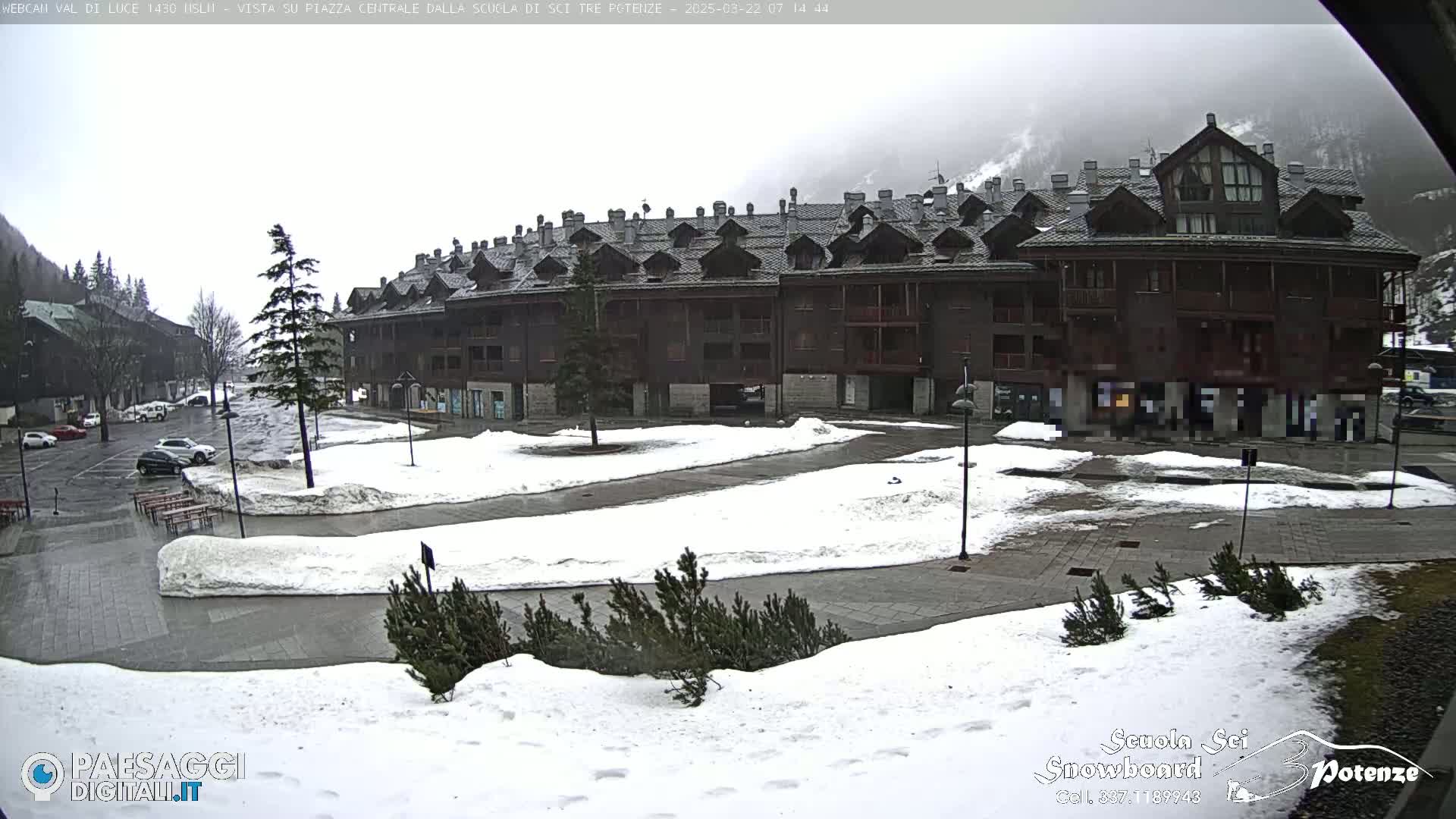 A snow-covered plaza with a large, multi-story building in the background under an overcast sky.