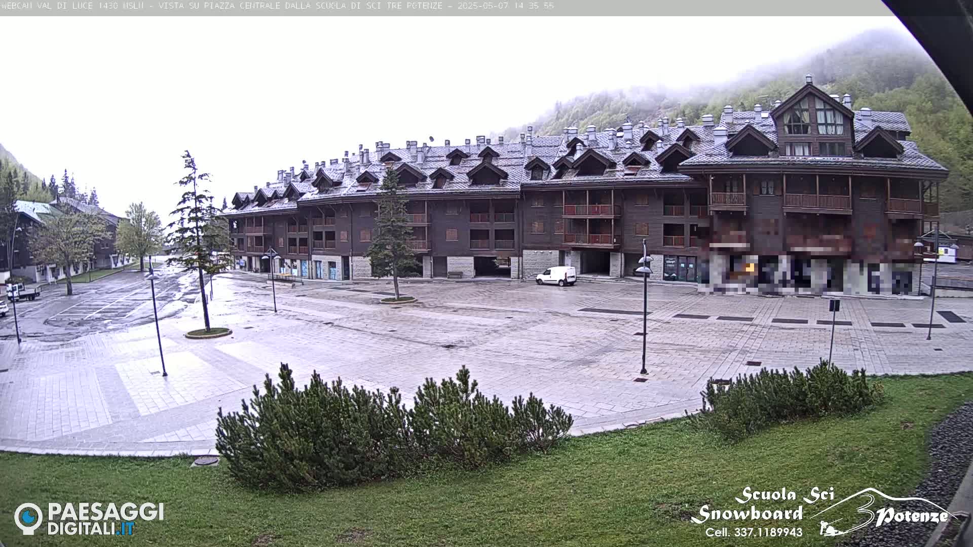 A large, multi-story building in a plaza with a mostly empty parking lot is seen on an overcast day.