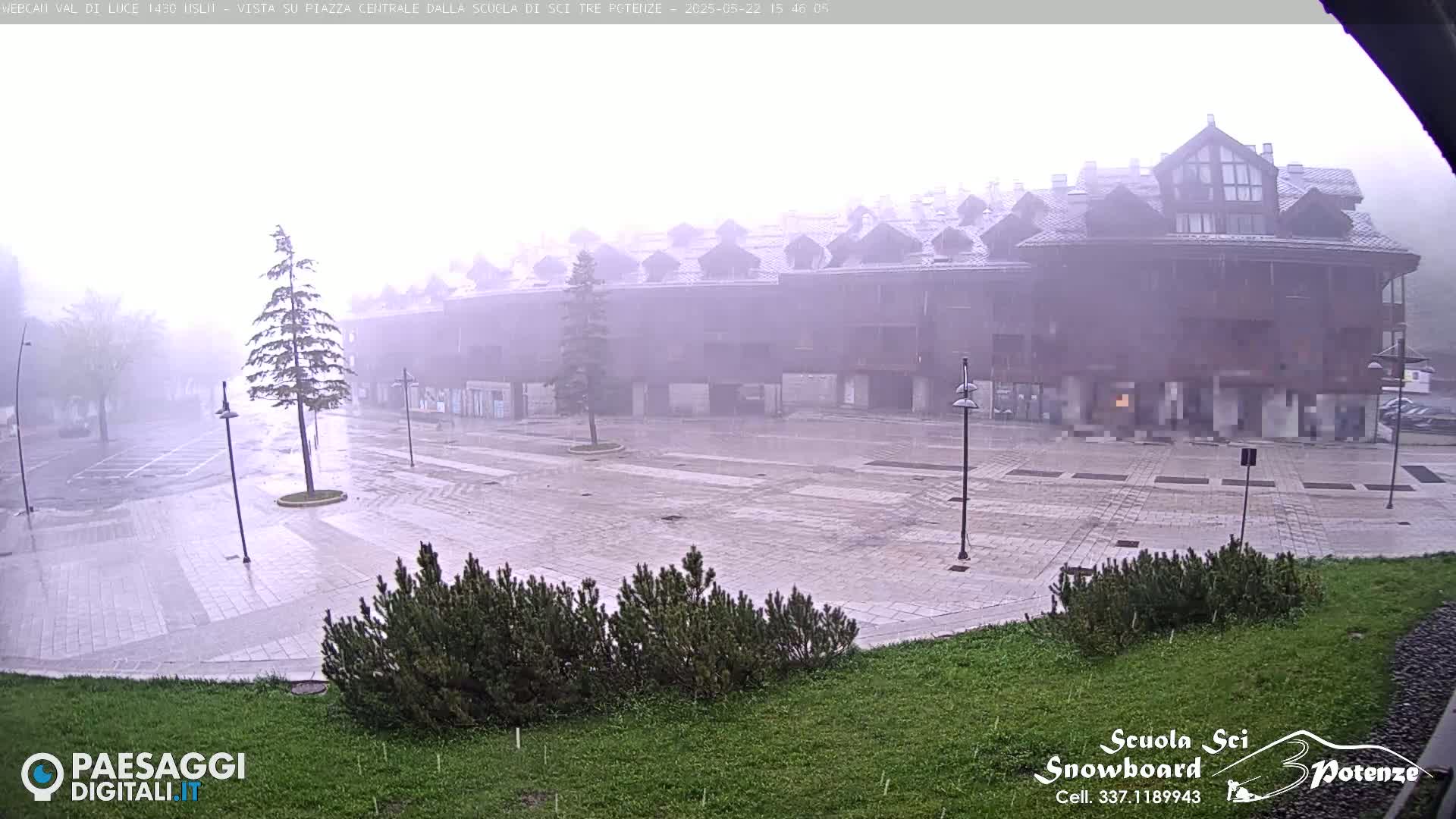A large, empty plaza in front of a multi-story building is seen during a heavy rainstorm.