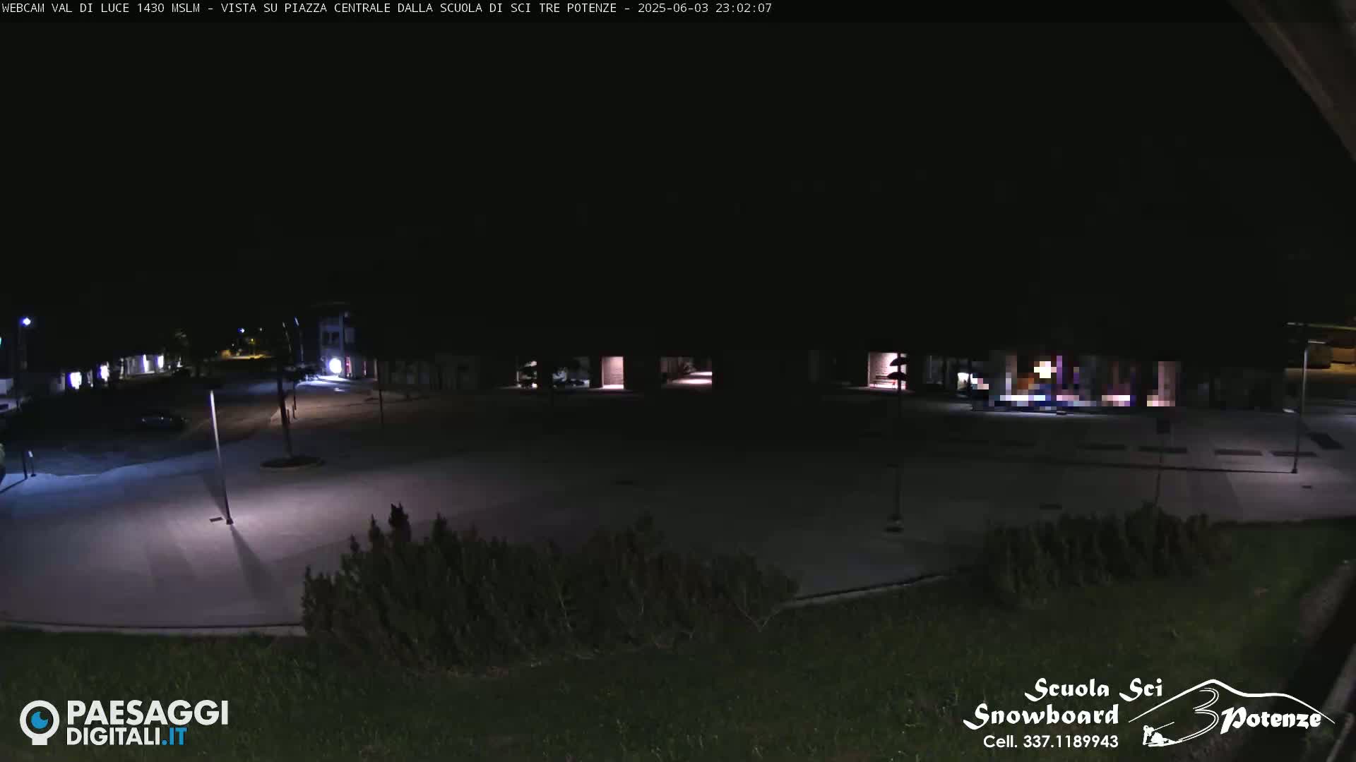 A dark, empty plaza at night is illuminated by a few streetlights.