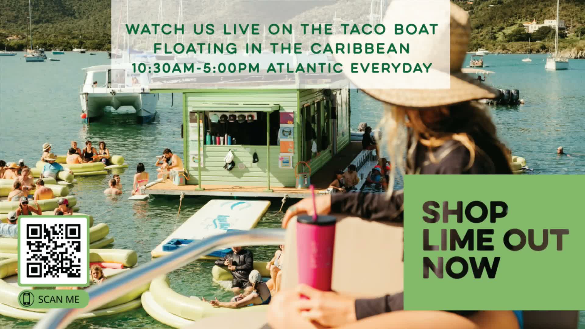 On a bright, sunny day, numerous people relax on and around a light green floating bar and yellow inflatables in the calm, clear waters of a tropical bay, with lush green hills and distant boats under a clear sky, as viewed from behind a person holding a pink tumbler.