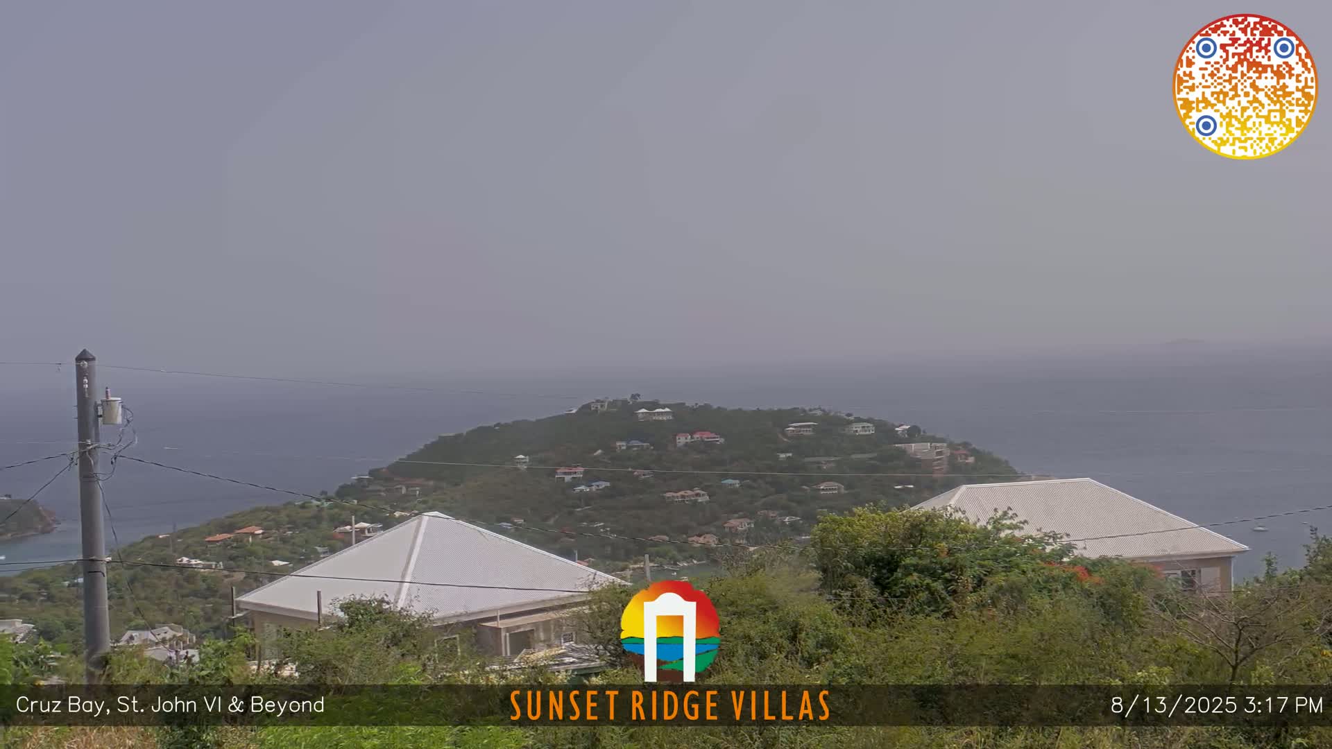 A hazy view shows a coastal scene with houses on a hillside overlooking the ocean, and more houses in the foreground.