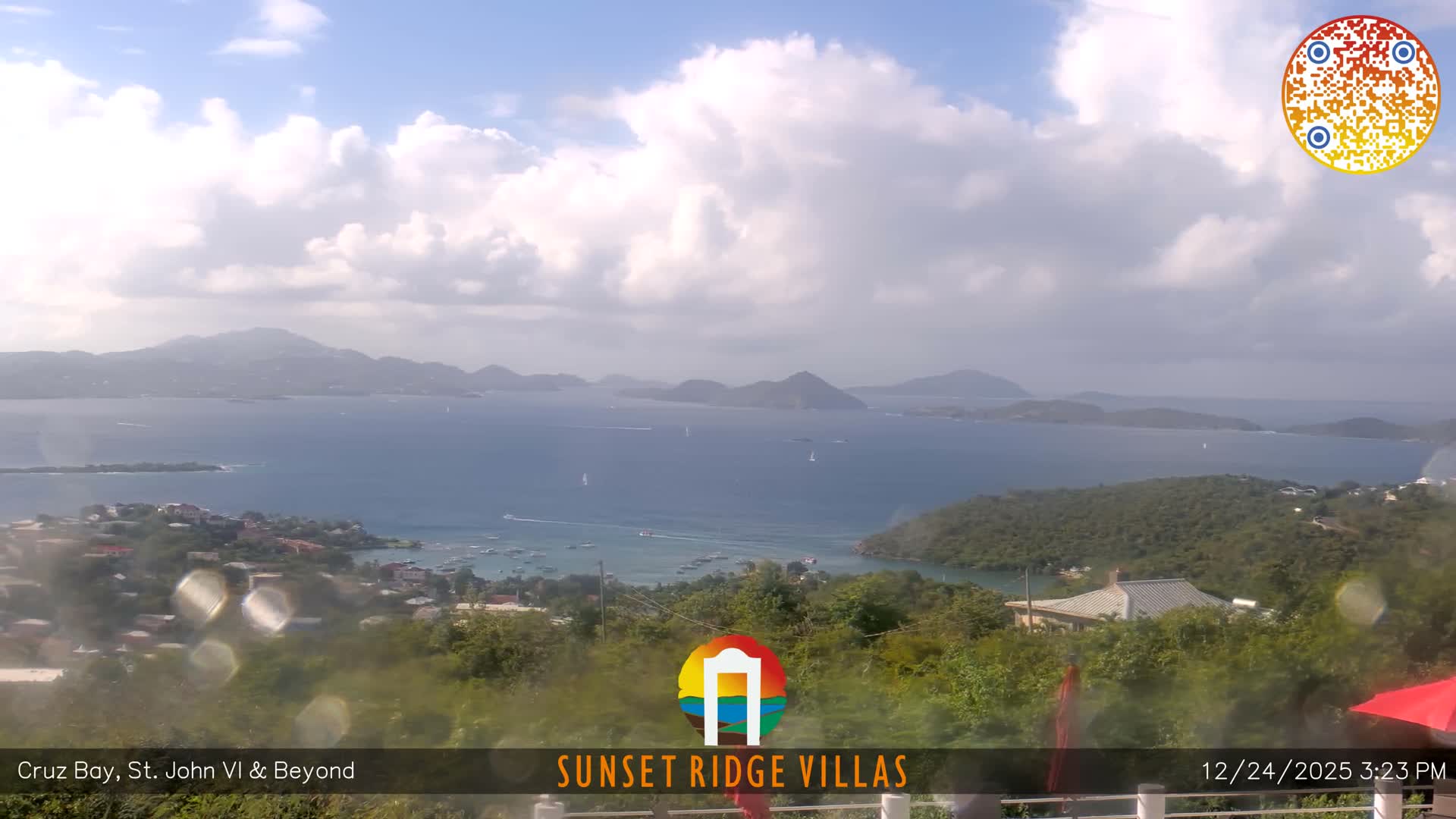 A wide, dark early morning view reveals distant twinkling city lights along a dark coastline under a clear sky, with faint mist or low clouds obscuring the immediate foreground.