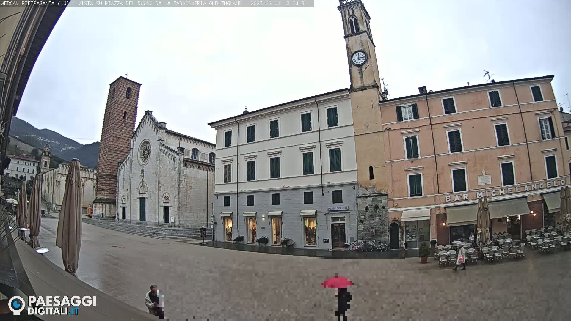 A town square with a church, shops, and a clock tower is shown on a wet, overcast day.