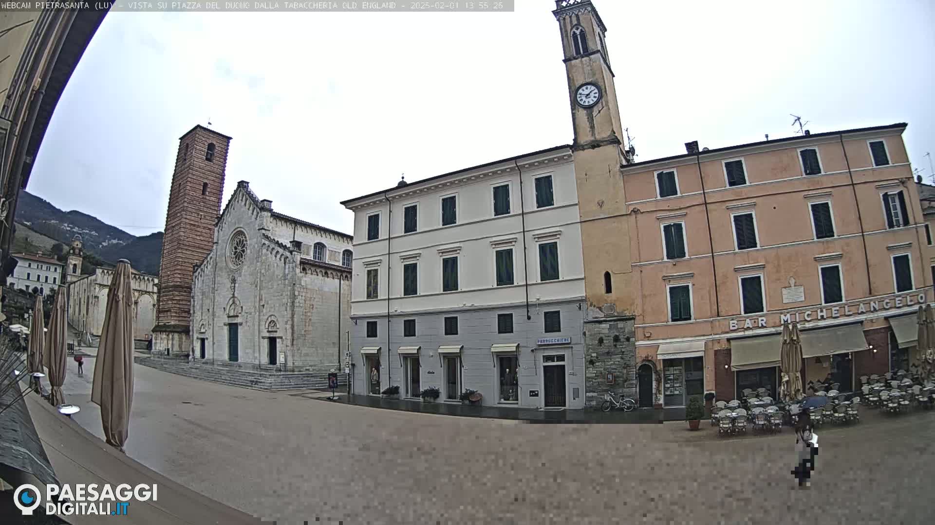 A town square with a large church and several buildings, under an overcast sky.