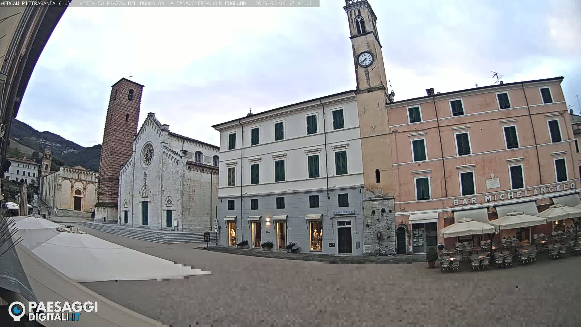 A town square is shown with a church, clock tower, and several buildings, under an overcast sky.