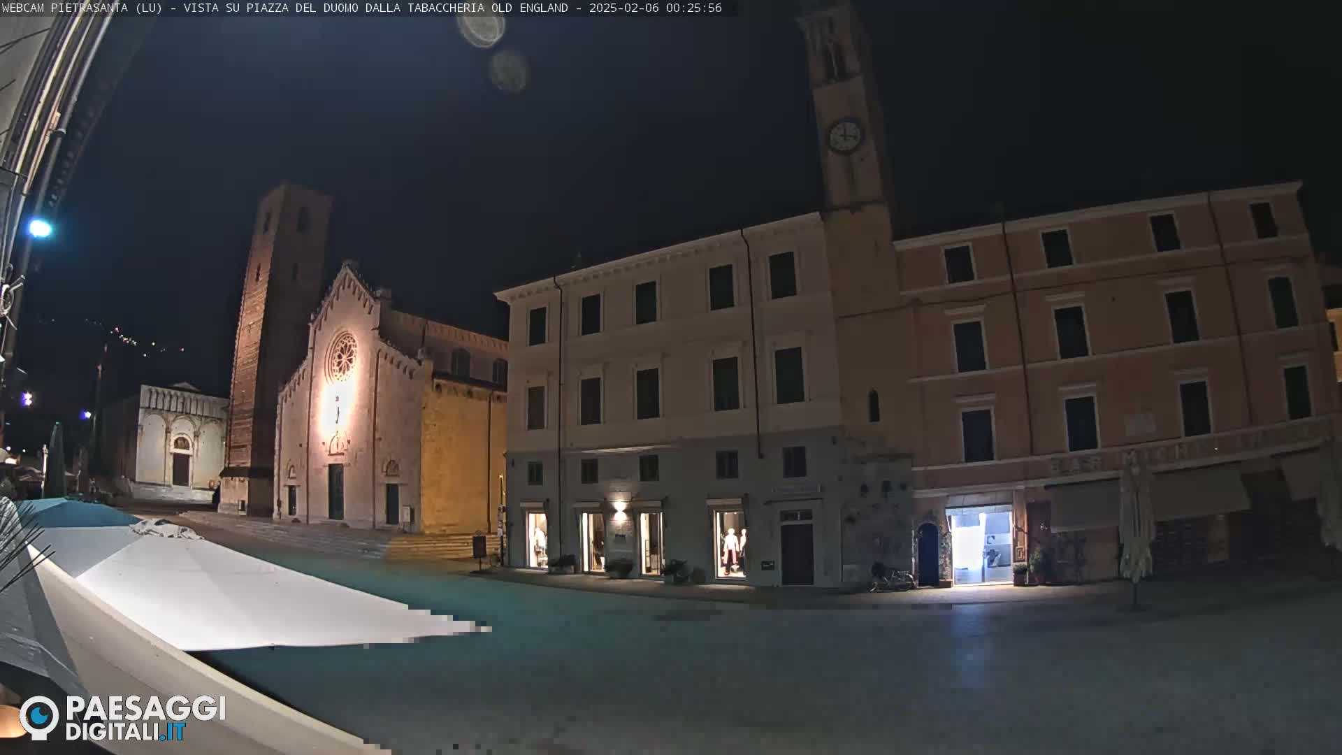 A nighttime view of a town square with a church and several buildings, under a clear, dark sky.