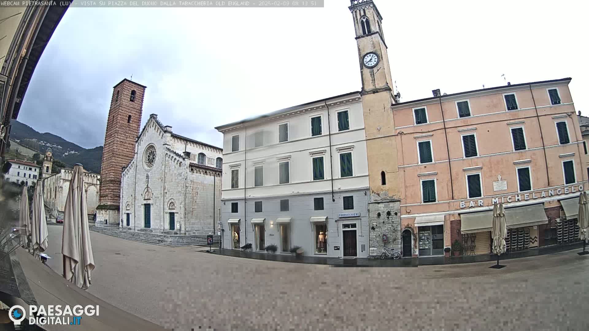 A town square with a large church and several buildings, under an overcast sky.