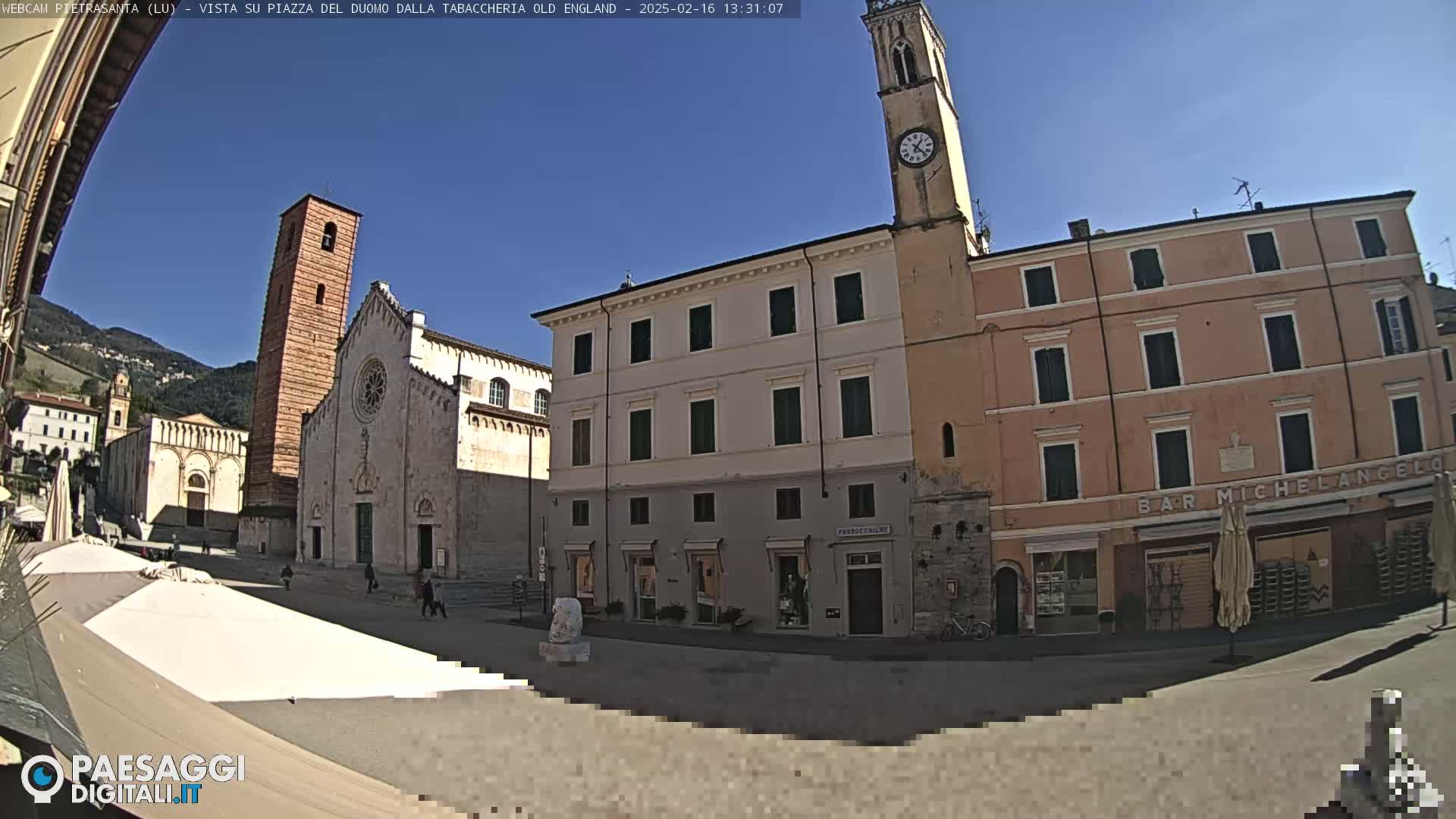 A town square with a cathedral and other buildings is seen on a sunny day.