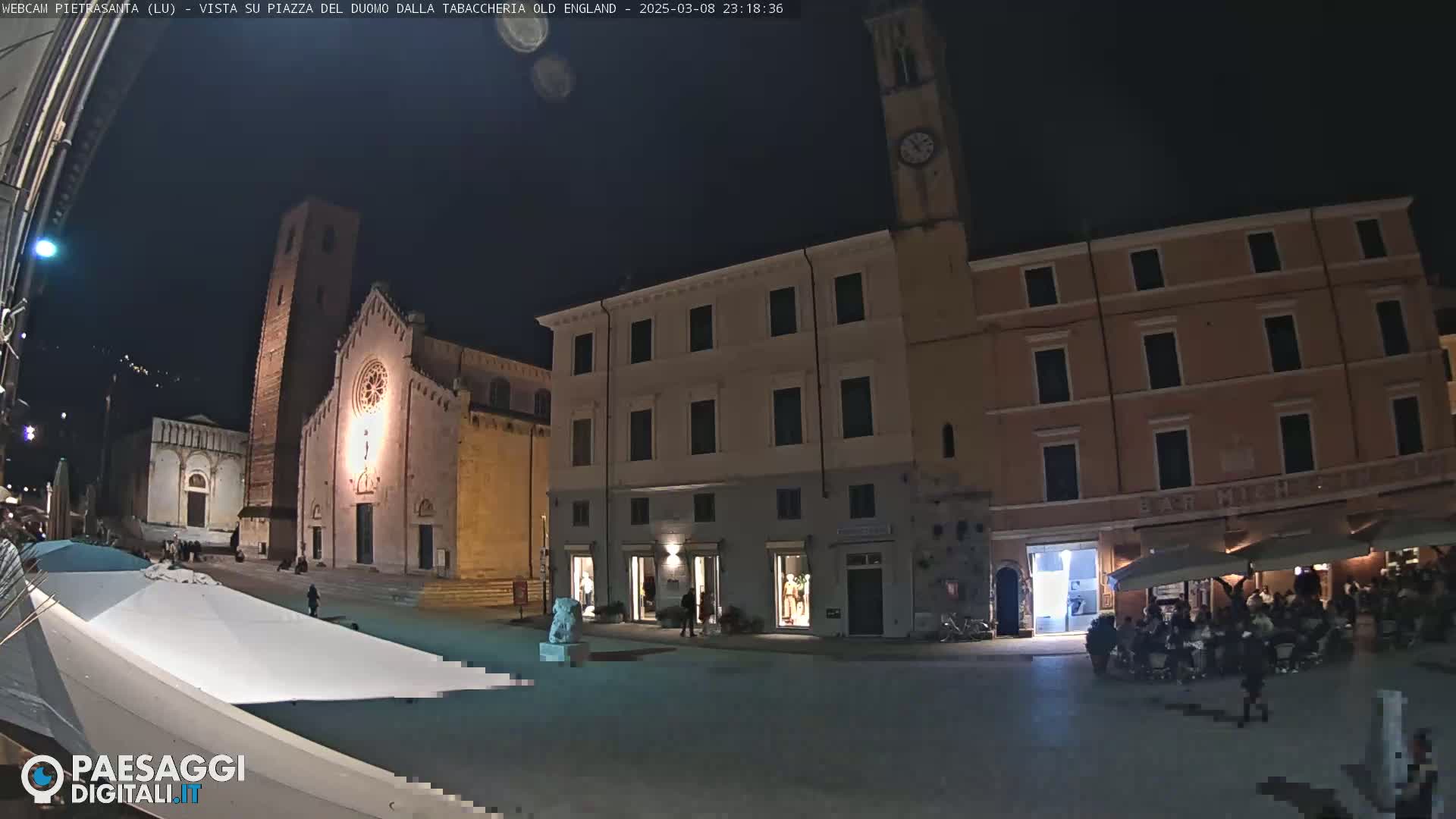 A nighttime view of a town square with a church and several buildings, under a clear, dark sky.