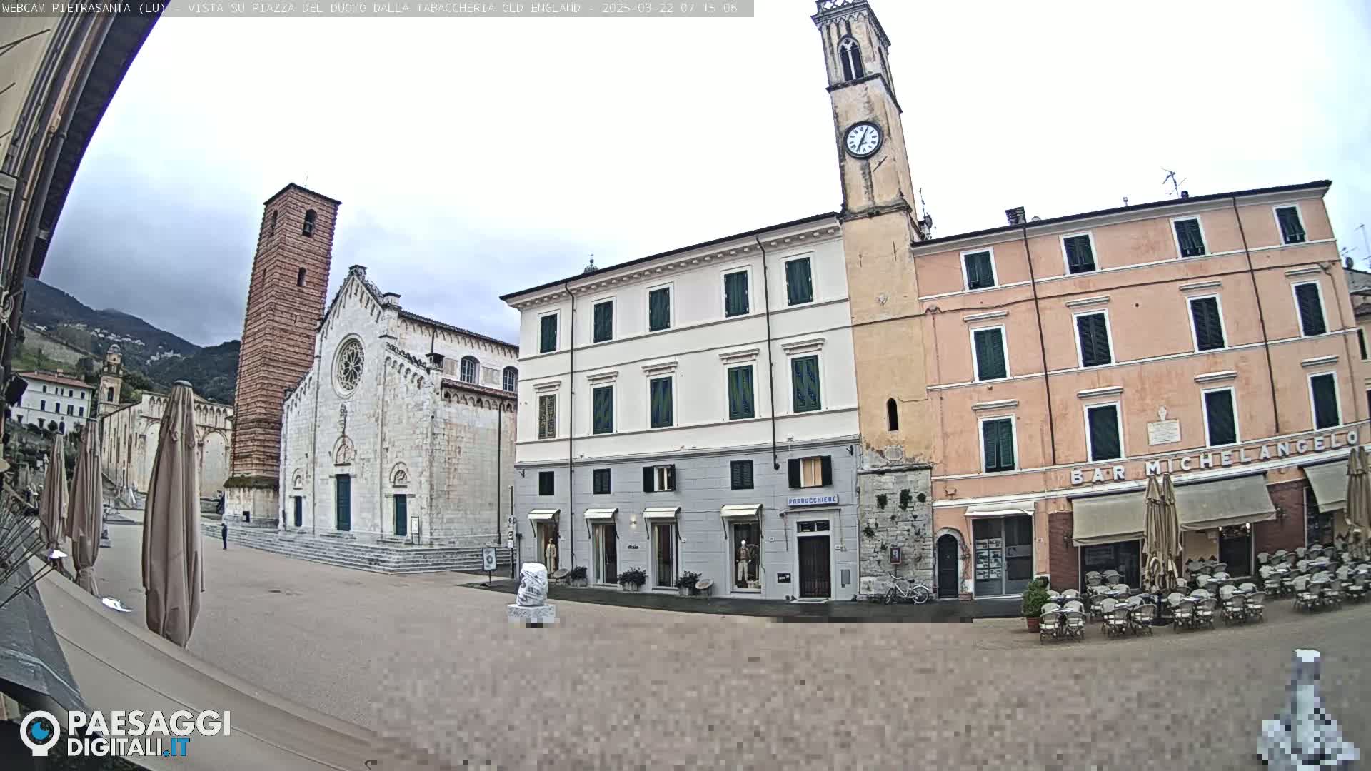 A town square with a large church, clock tower, and buildings, under an overcast sky.