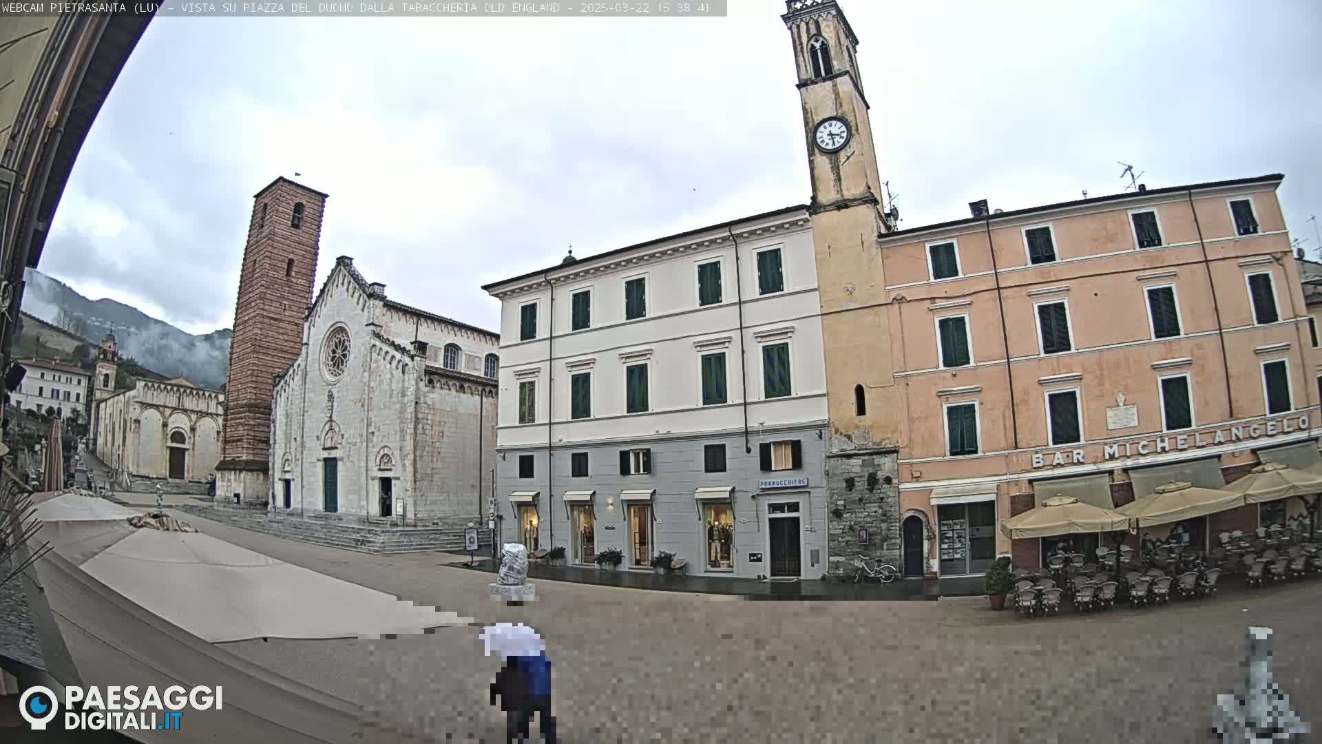 A town square with several buildings, including a church and a bar, under an overcast sky.